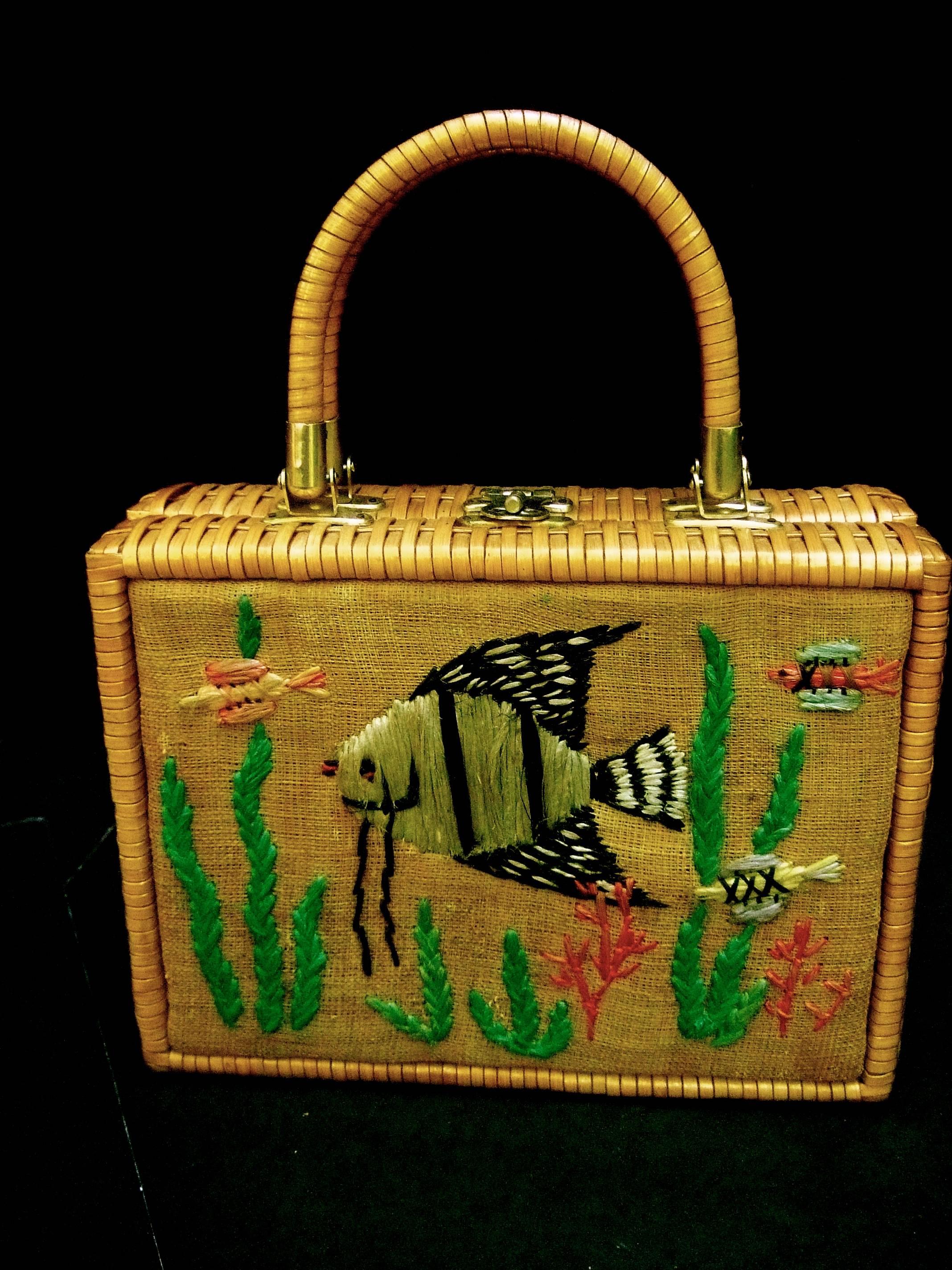 Whimsical wicker straw embroidered sea life handbag ca 1960
The woven wicker retro handbag is designed with a burlap 
front panel. Embroidered with schools of fish, seaweed 
and coral branches 

The twins handles, sides and back exterior are