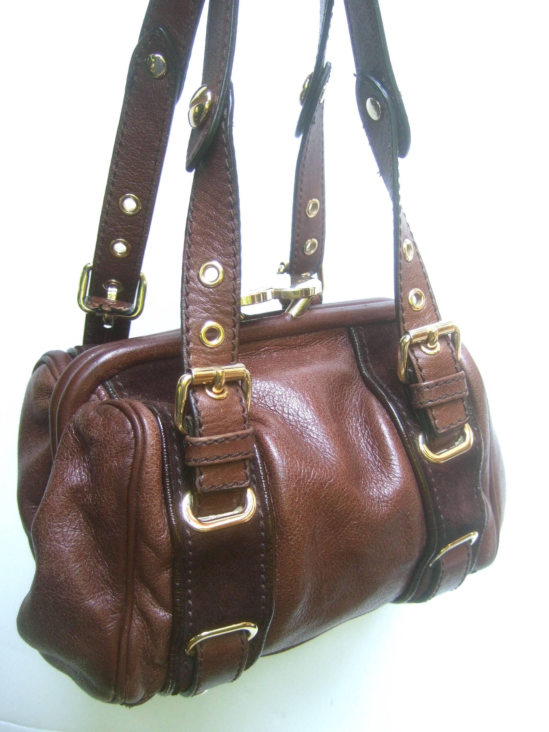Marc Jacobs Italian brown leather diminutive handbag 
The stylish compact Italian handbag is covered with supple
mocha brown leather 

Designed with sleek gilt metal hardware and buckles 
Accented with a pair of brown suede vertical stripes
The kiss