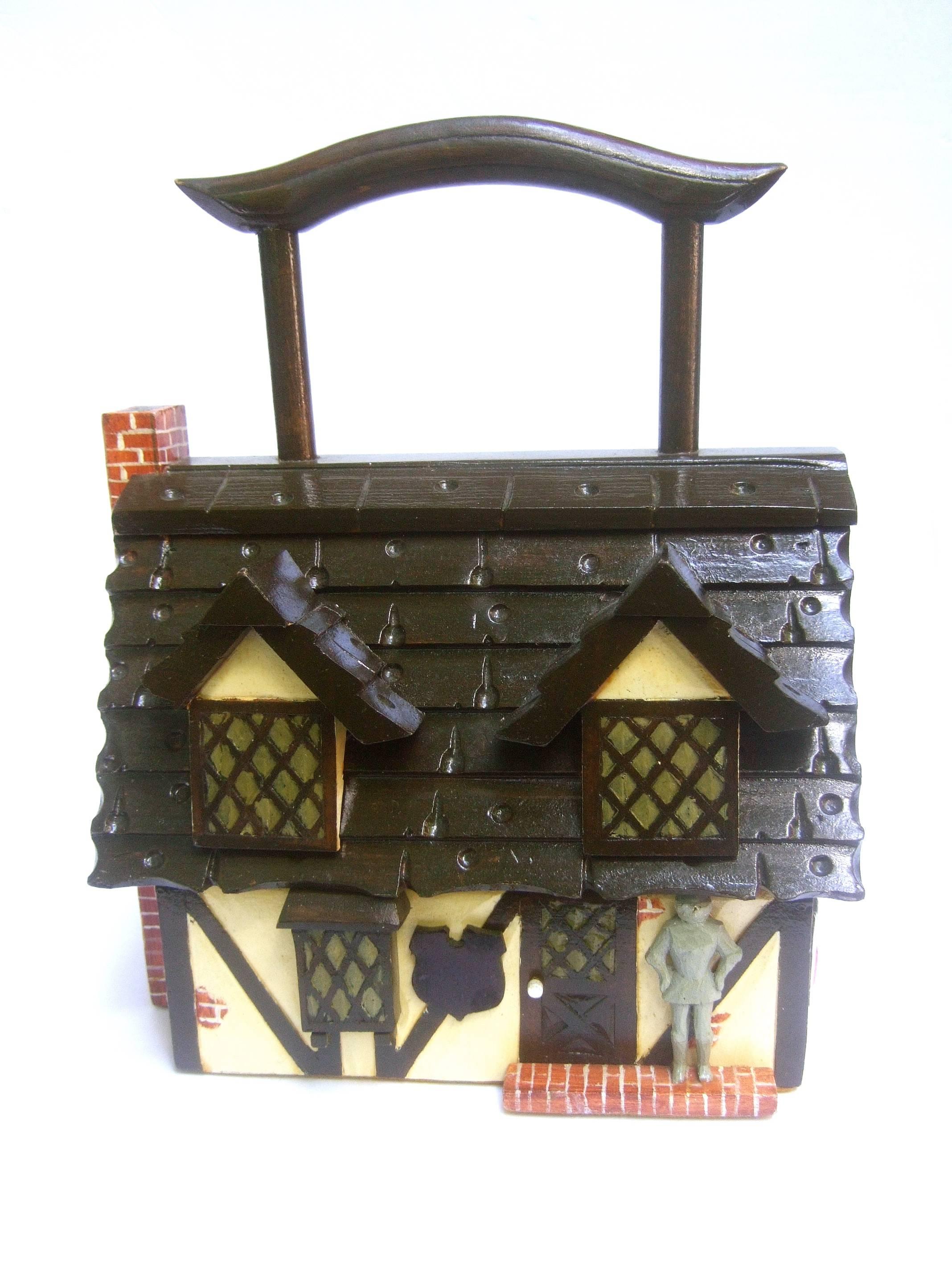 Whimsical artisan wood tudor house box purse c 1970
The quirky handmade wood house theme handbag
is designed in the style of an English tudor cottage 

Presiding at the front entrance is a knight figure
The front door and windows have hand painted  