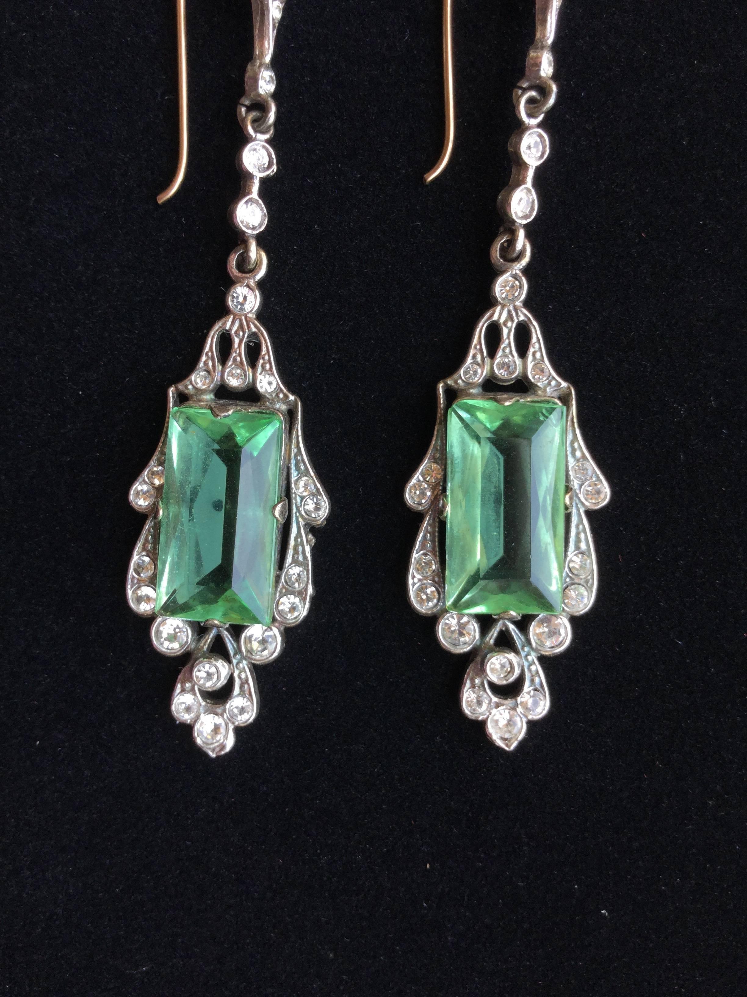Romantic antique drop earrings of sterling silver and peridot colored faceted
pastes enlivened with bezel set crystals. Gold filled wires. Drop: 2.5 inches.  Width: 5/8th of an inch at their widest. English c.1905. Unsigned. Tests as sterling