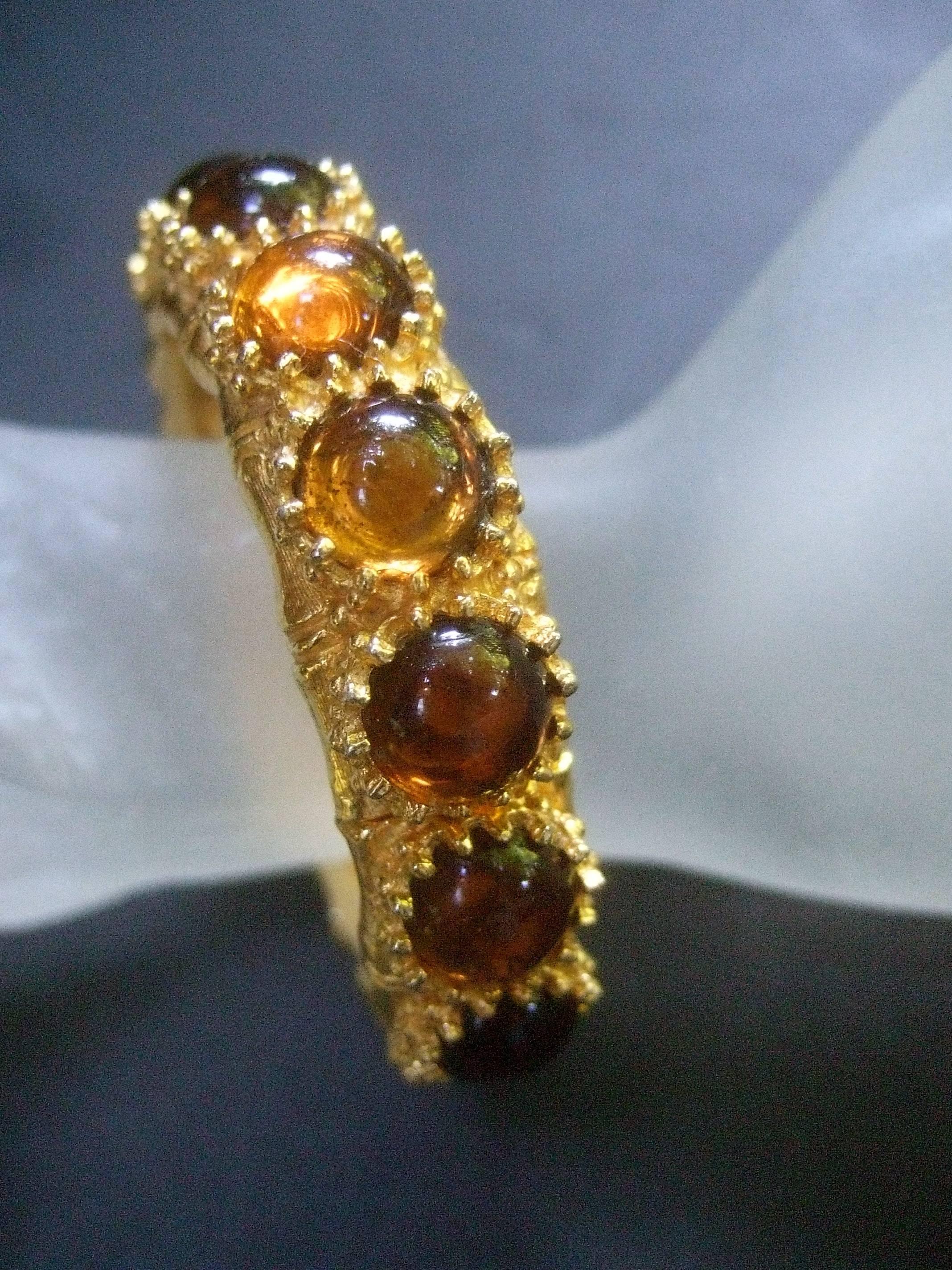 Ken Lane amber glass cabochon gilt metal bracelet c 1970s
The stylish designer costume clamper bracelet is adorned
with a series of honey color glass cabochons 

The hinged bangle is plated with gilt metal 
that has a bamboo design framing the