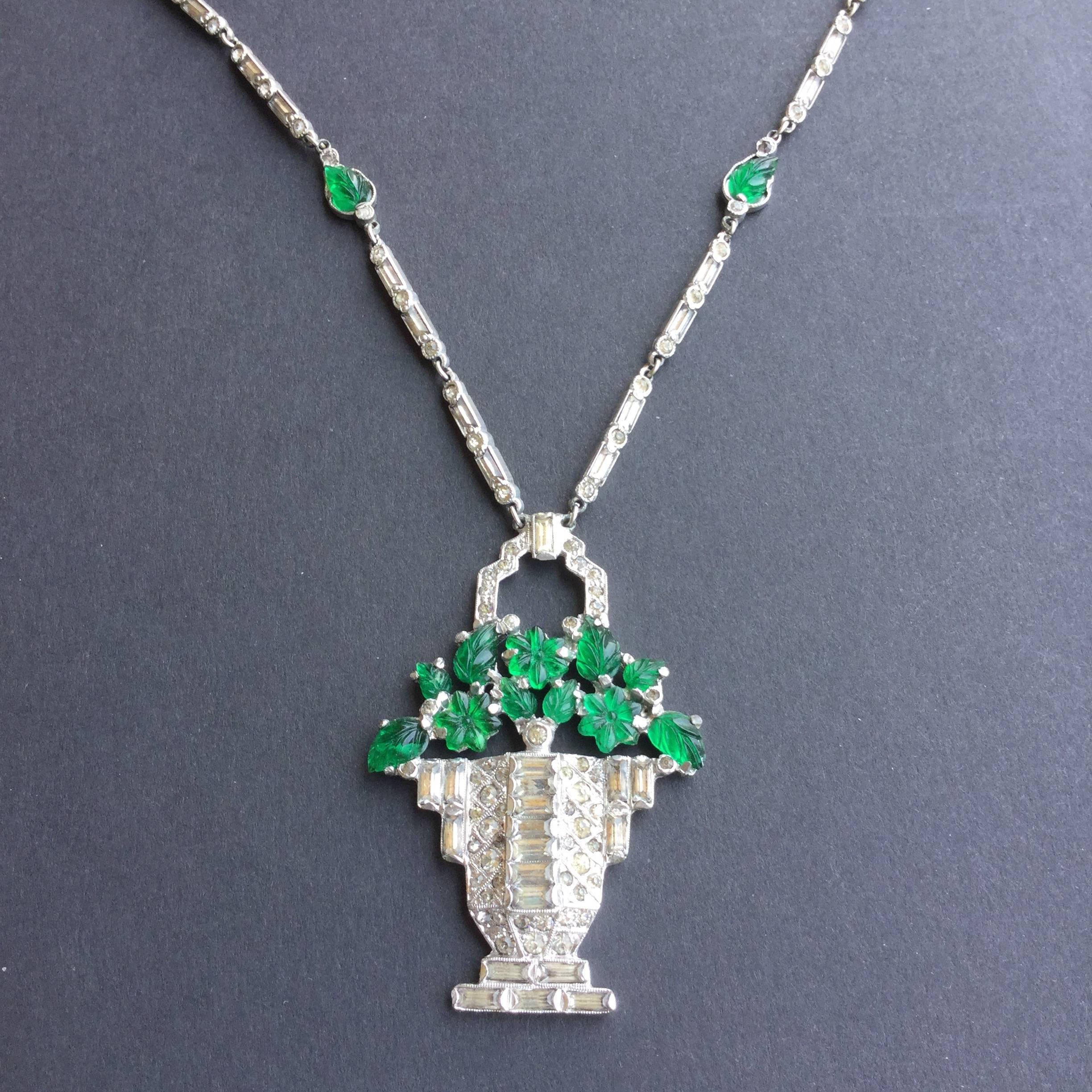 Rare Cartier Style Pendant Necklace from the 1930's. Like all the best Art Deco costume jewelry;  the pastes are bezel set. Here glass floral emeralds rise from a crystal encrusted urn. Baguettes and round cut faux diamonds decorate the urn and