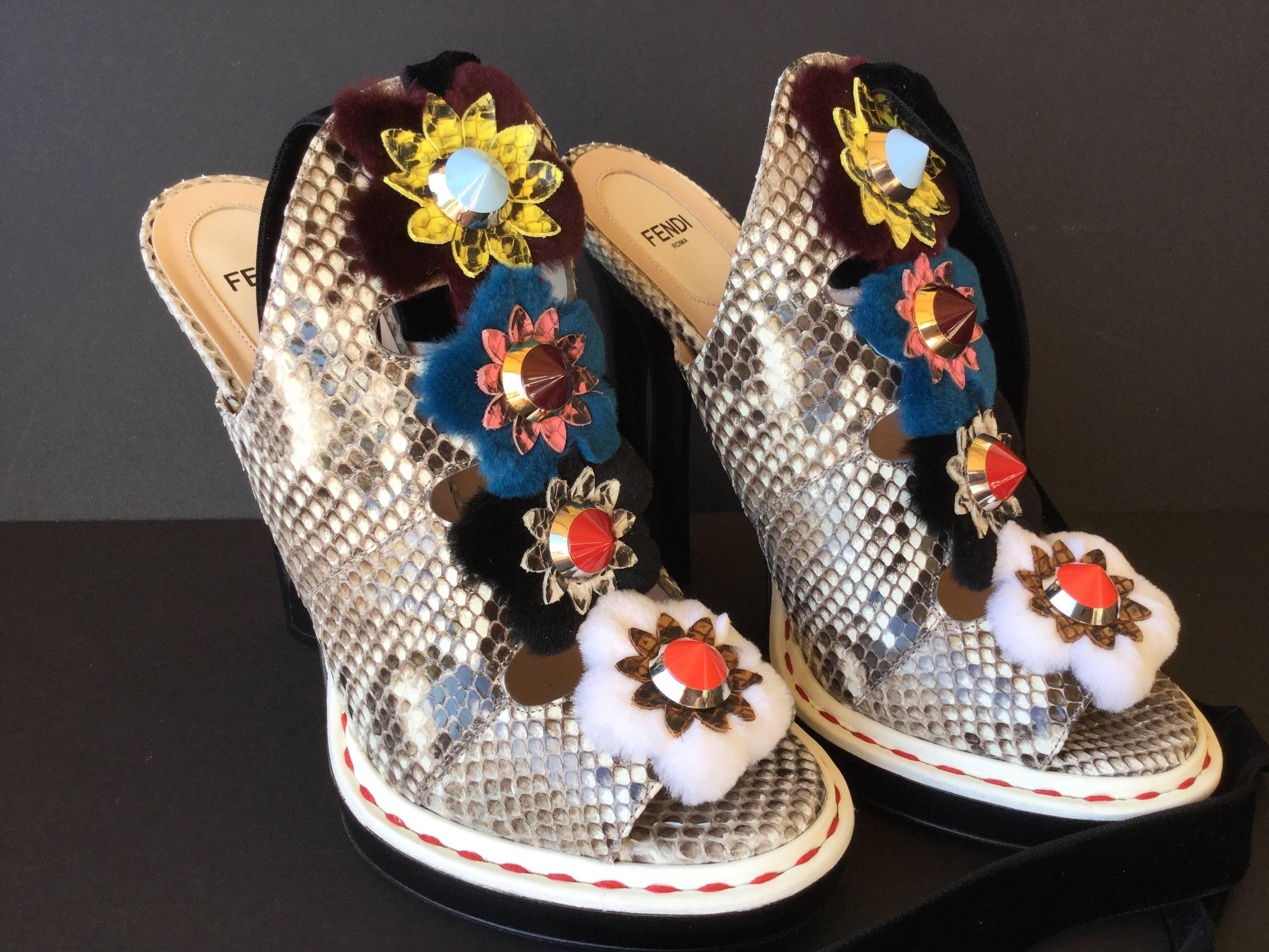 Spectacular 2016 Fendi Flowerland peep toe mules. Python upper adorned with eye catching multi colored flowers crafted from leather, fur, and enamel spikes. Chunky 5 inch teardrop stacked heel with an optional velvet strap that can be worn around