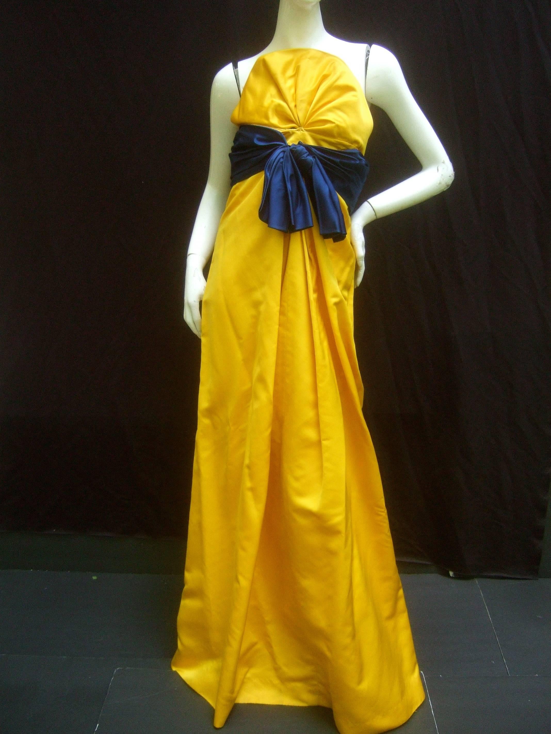 Bill Blass Opulent golden satin gown for Neiman Marcus c 1990s
The elegant gown is designed with luminous golden
yellow duchess satin fabric

The bodice is distinguished with a rounded scalloped panel
The sweeping gown is embellished with a lapis