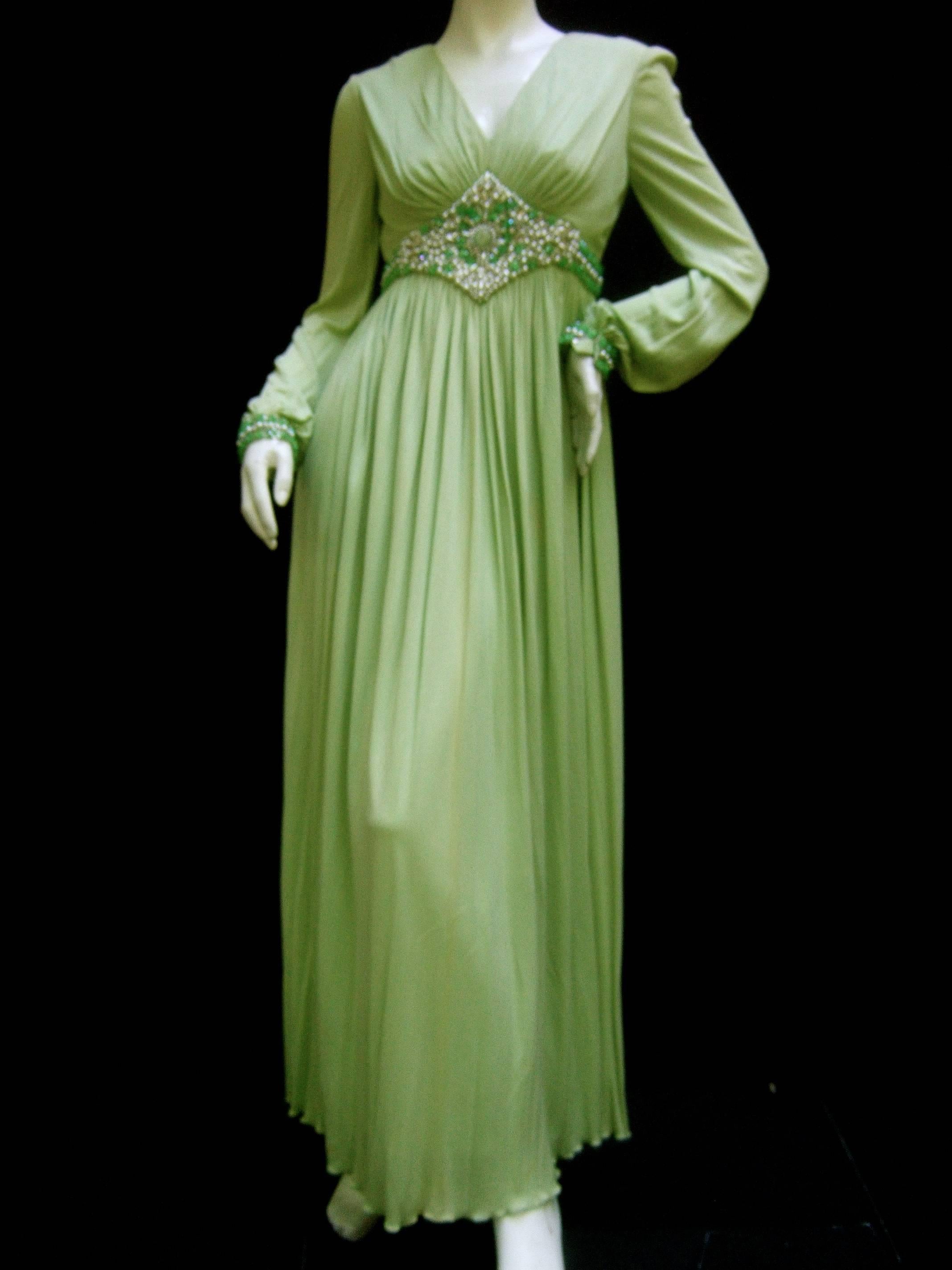 1970s Mint green matte jersey pleated gown designed by Malcolm Starr
The elegant Grecian style jersey gown is embellished with jeweled 
faux pearls and lucite mint green crystals. The center stone is a large
opaque green glass cabochon that runs