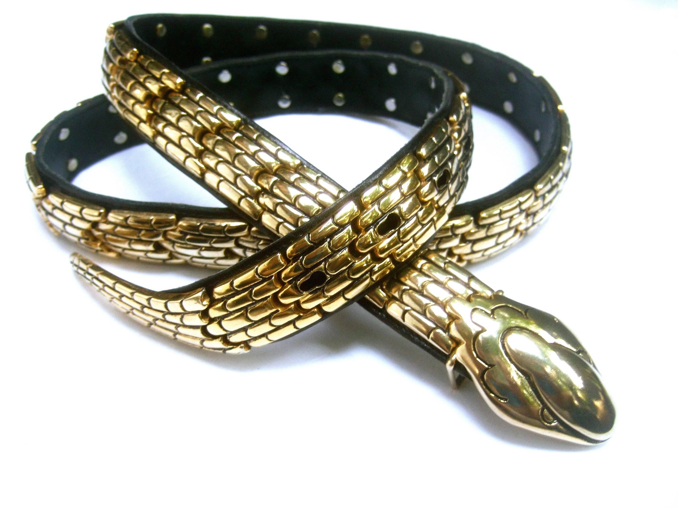 Avant-Garde Italian articulated gilt metal serpent belt
The unique belt is constructed with heavy gilt metal
links with impressed designs that emulate scales 

The series of gilt metal links are secured to a black 
leather belt. The buckle is