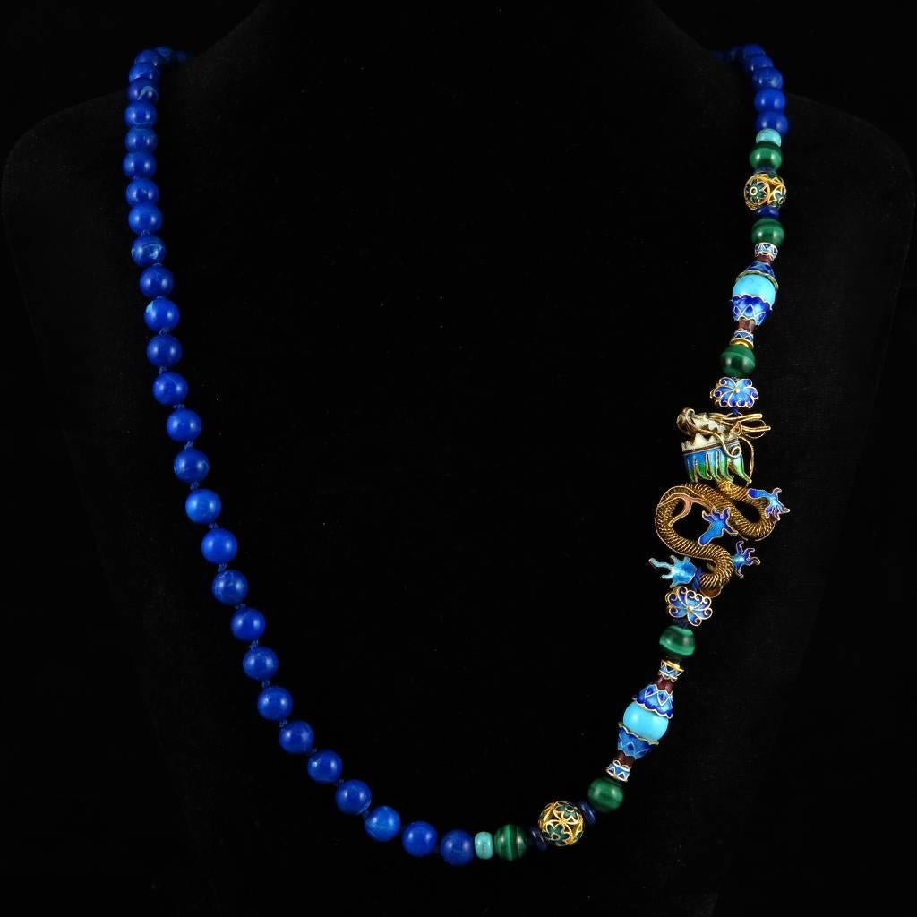 Superb hand knotted lapis beaded necklace featuring an incredible gilded silver and enamel dragon. Asymmetrical as the dragon is worn to one side. This mythical creature is highly detailed in gold plated vermeil silver with intricate twisted rope