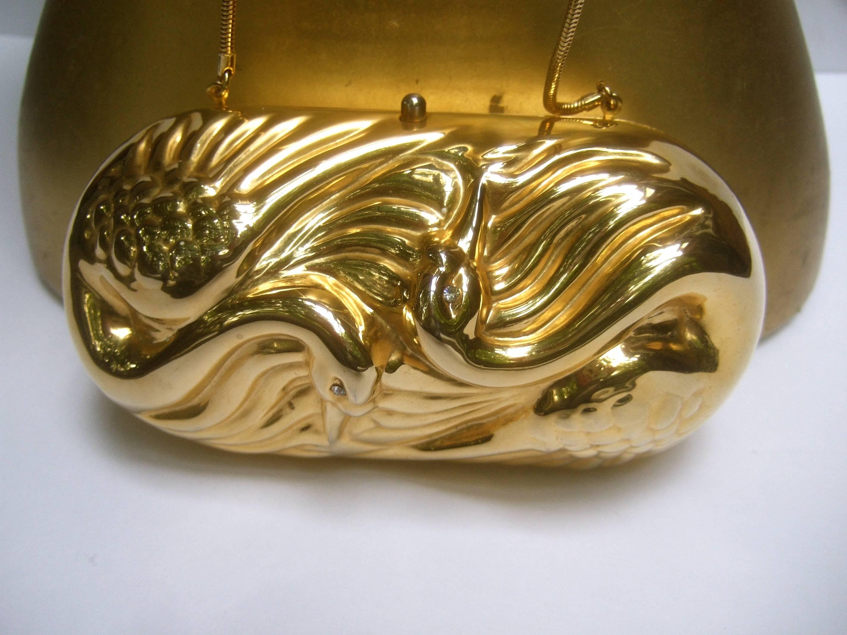 Saks Fifth Avenue Opulent gilt metal Italian evening bag c 1980
The elegant minaudière is designed with a pair of stylized 
repousse swans on the front exterior 

Each of the swans is embellished with a tiny diamante 
crystal eye. The versatile