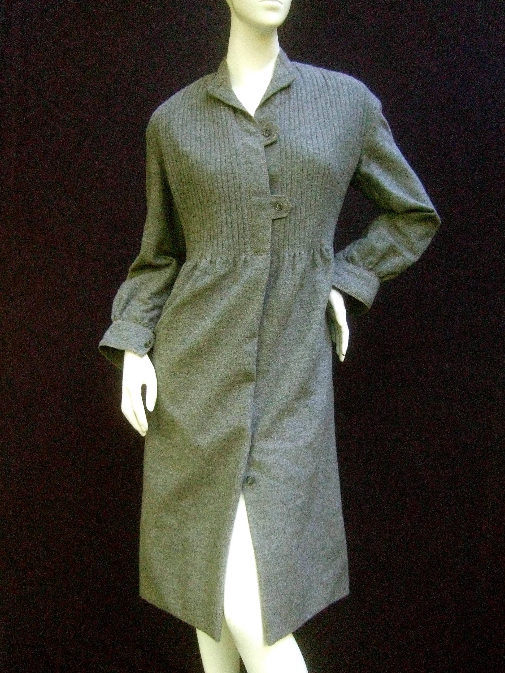Galanos Luxurious gray flannel coat dress c 1970
The soft plush flannel wool dress is designed 
with subtle vertical ribbed detail across the 
bodice

Accented with a series of small gray lucite
buttons that run down the center front 
Partially