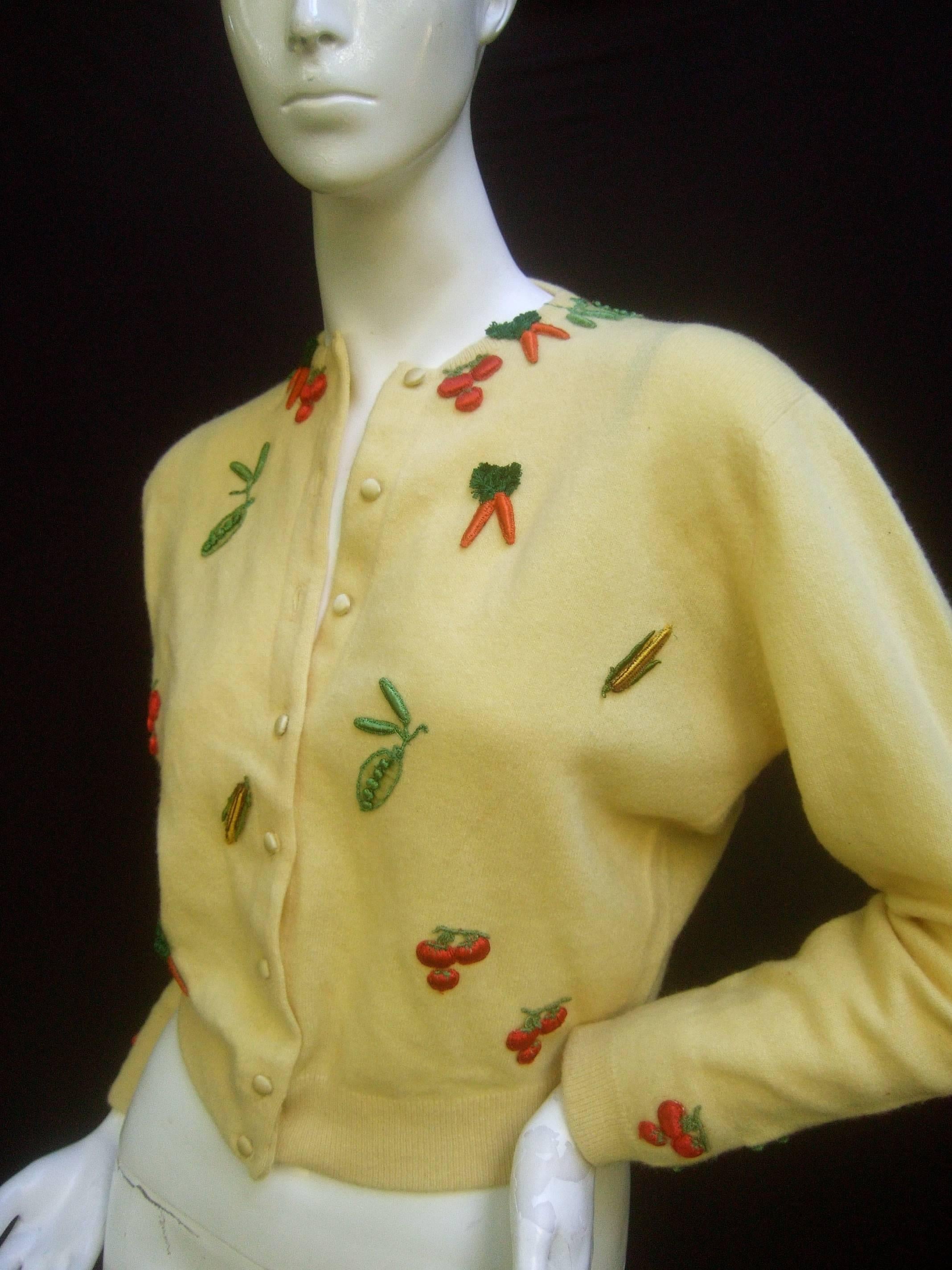 Whimsical buttercup yellow cashmere vegetable theme cardigan c 1960s
The unique cashmere cardigan is designed with a collection 
of appliqué vegetables

The vegetable garden of carrots, tomatoes, peas and corn stalks  
are scattered throughout the