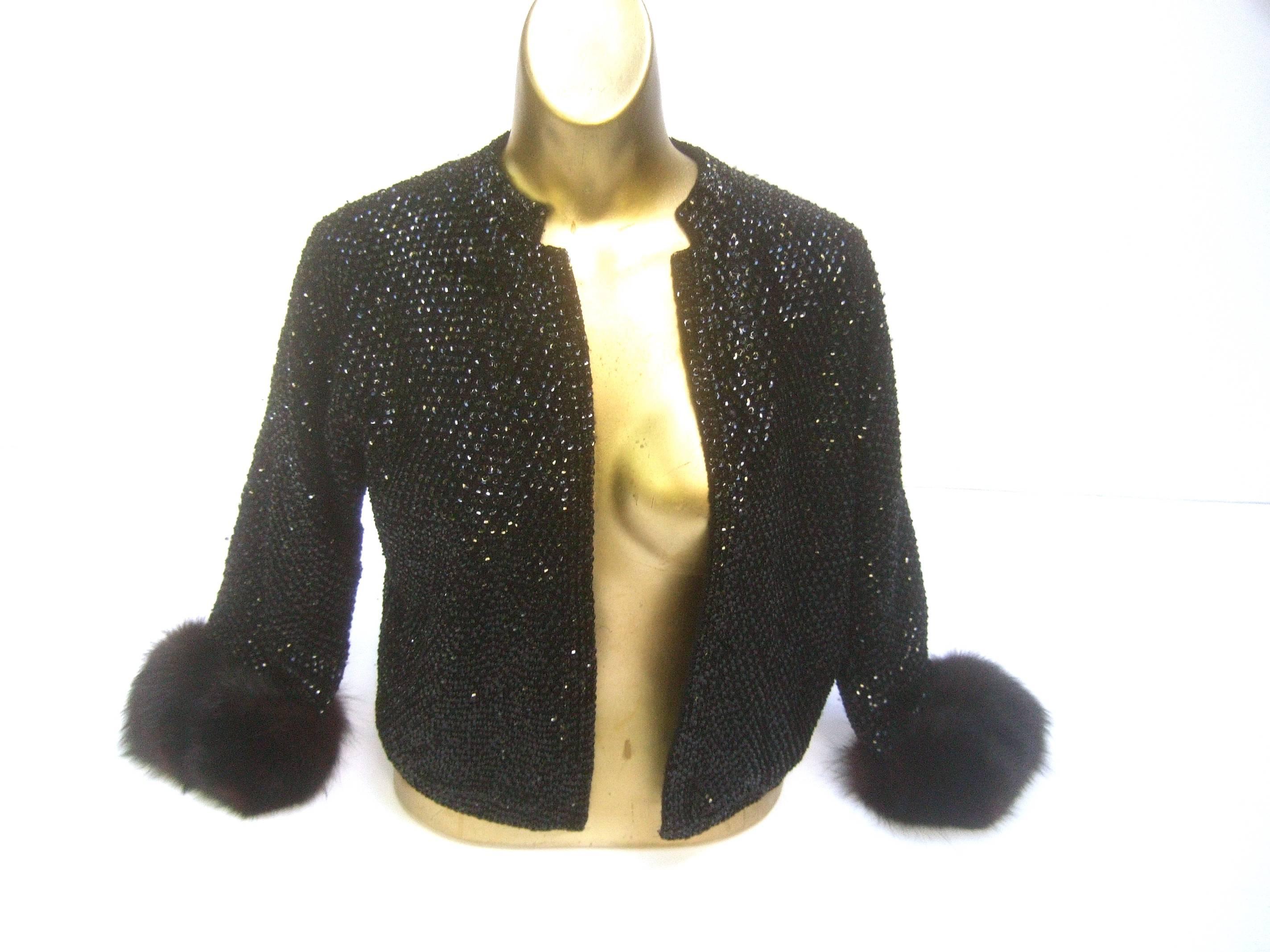 Saks Fifth Avenue Elegant black sequined fox trim cardigan c 1970s
The stylish wool knit cardigan is embellished with contiguous 
glittering black sequins throughout 

The cuffs are adorned with dark brown fluffy fox fur trim 
Makes a very chic