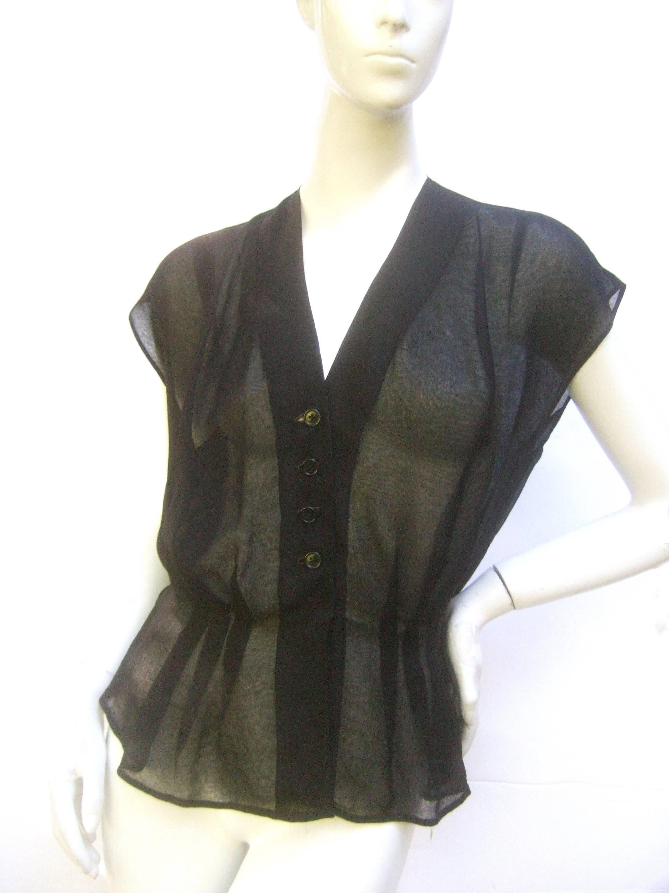 Christain Dior sheer black silk blouse c 1970
The elegant black sheer silk short sleeve 
blouse buttons down the front with a set
of small black lucite buttons

The sheer illusion silk fabric may require 
a camisole and or black lace bra