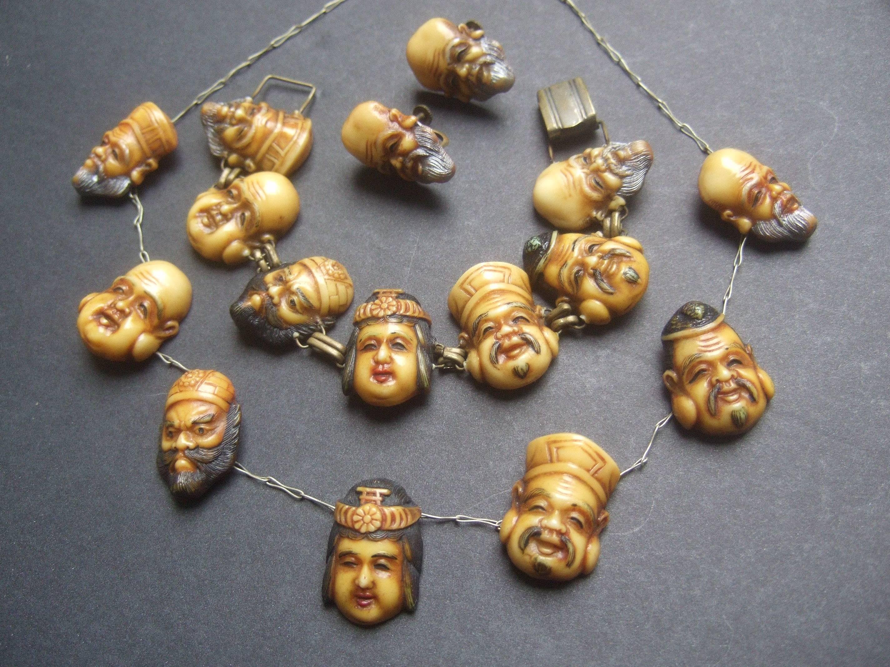 Seven Japanese gods of good fortune necklace set c 1940s  
The unique artisan set consist of a choker necklace,
matching bracelet and a pair of screw back earrings 

The figural gods are designed with intricate carved  
resin with enamel detail. The