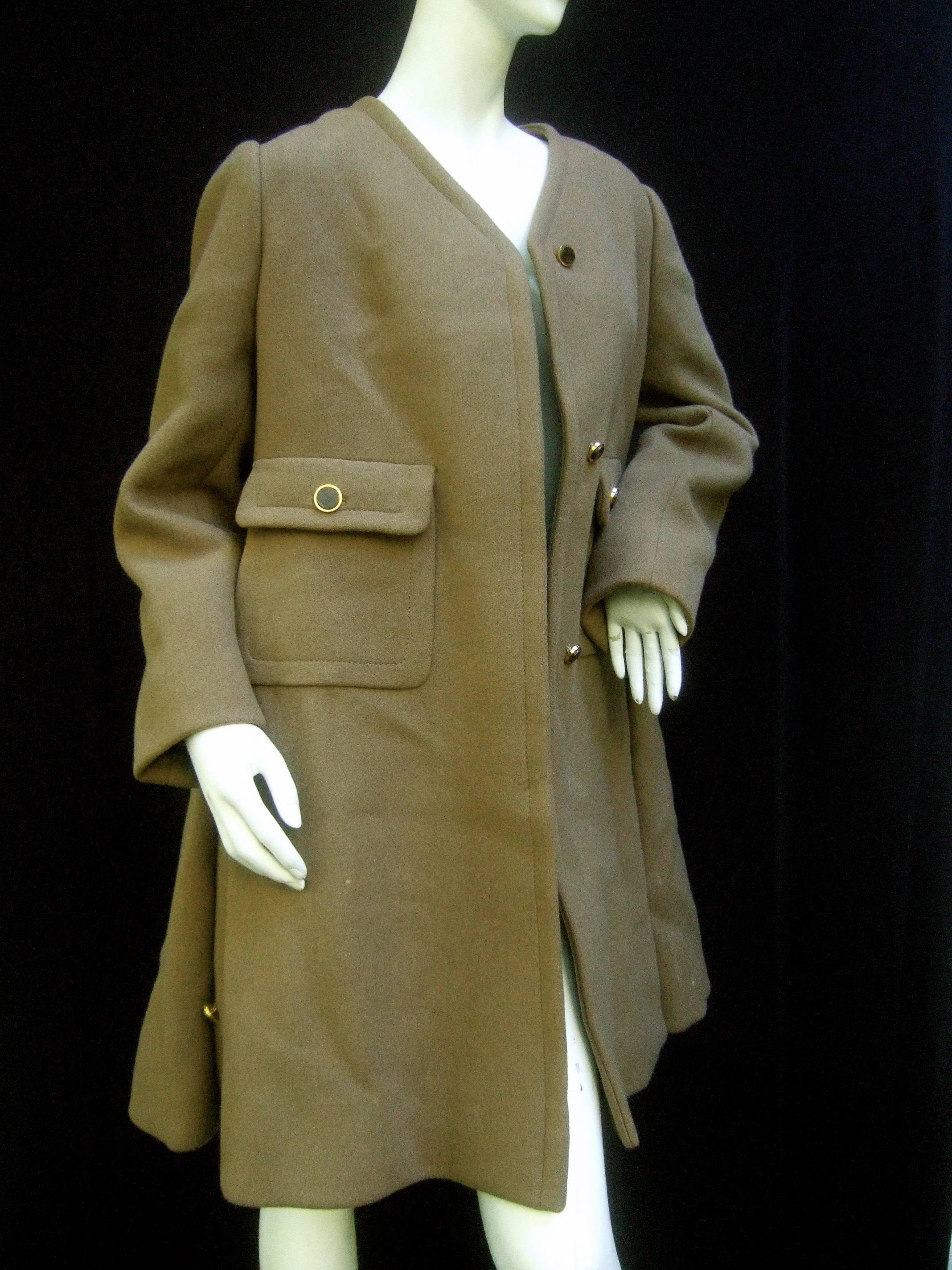 Galanos mocha brown wool winter coat c 1970
The stylish heavy gauge wool coat is designed 
in a light mocha brown shade

The chic retro coat secures with lucite tortoise
shell buttons with gilt metal bases 
The front midsection have a pair of flap