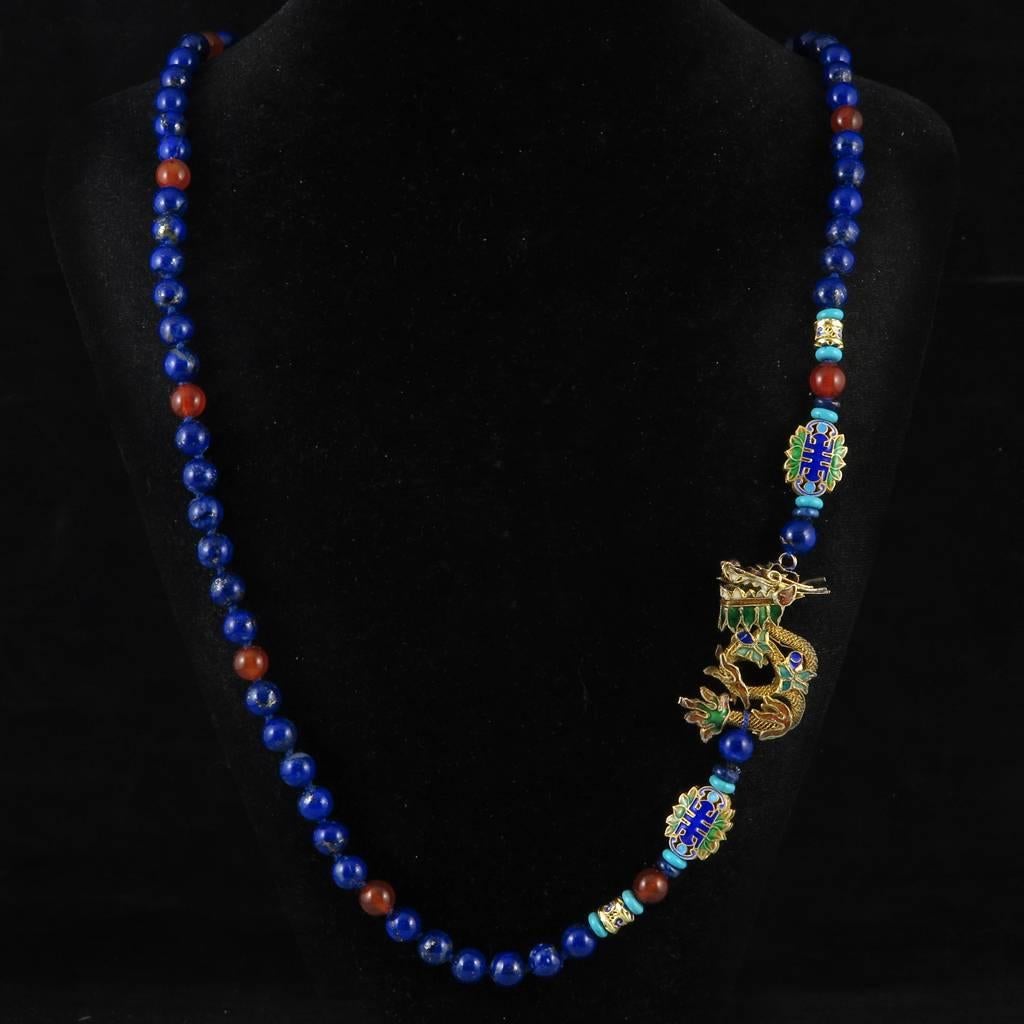 Superb hand knotted lapis beaded necklace featuring an incredible gilded silver and enamel dragon. Asymmetrical as the dragon is worn to one side. This mythical creature is highly detailed in gold plated vermeil silver with intricate twisted rope