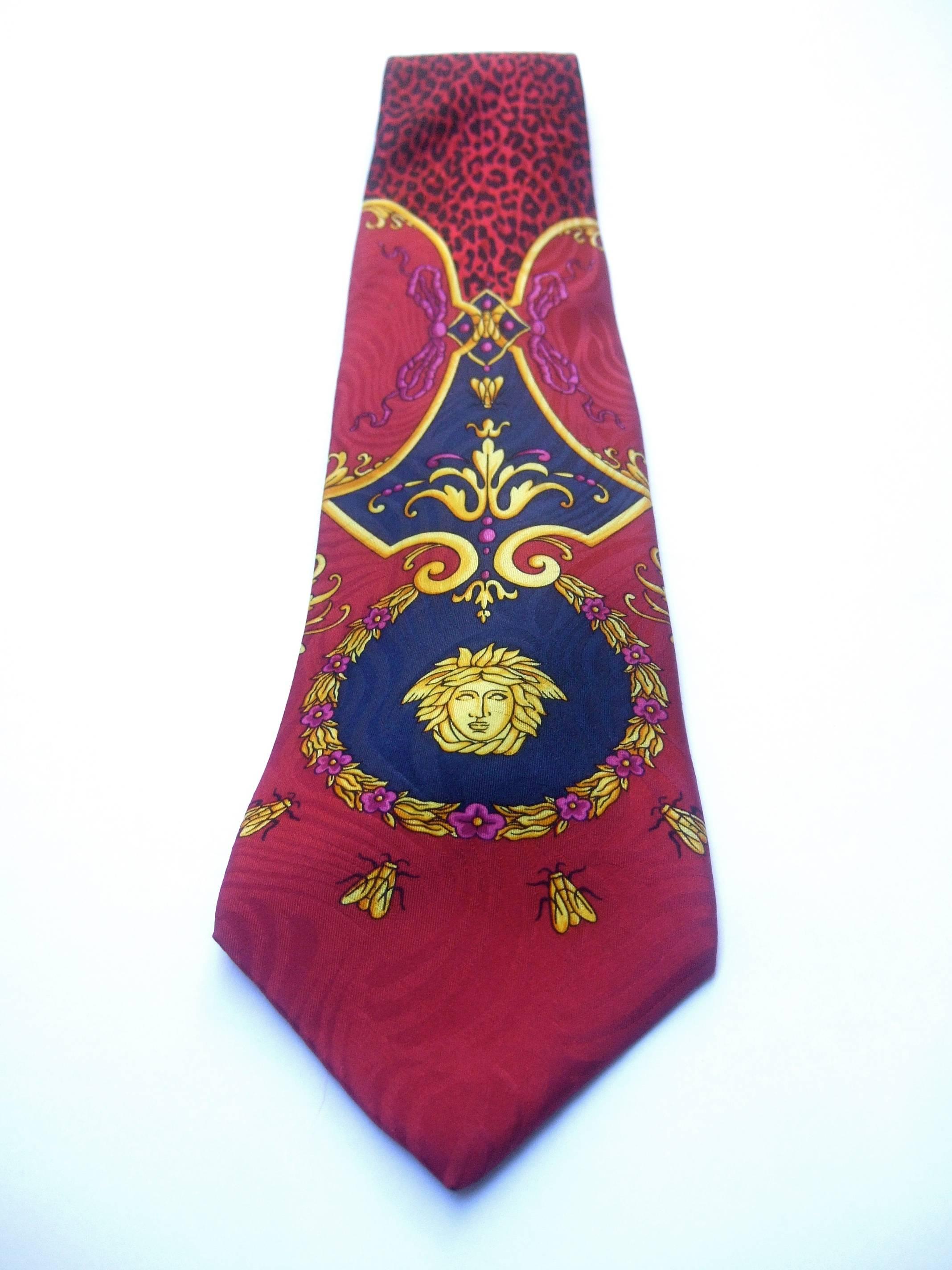 Gianni Versace Silk medusa animal jungle print necktie c 1990s 
The vibrant burgundy silk necktie is designed  
with Versace's signature medusa figure

Accented with a series of golden bees circling the medusa 
figure; swarming around a wreath of