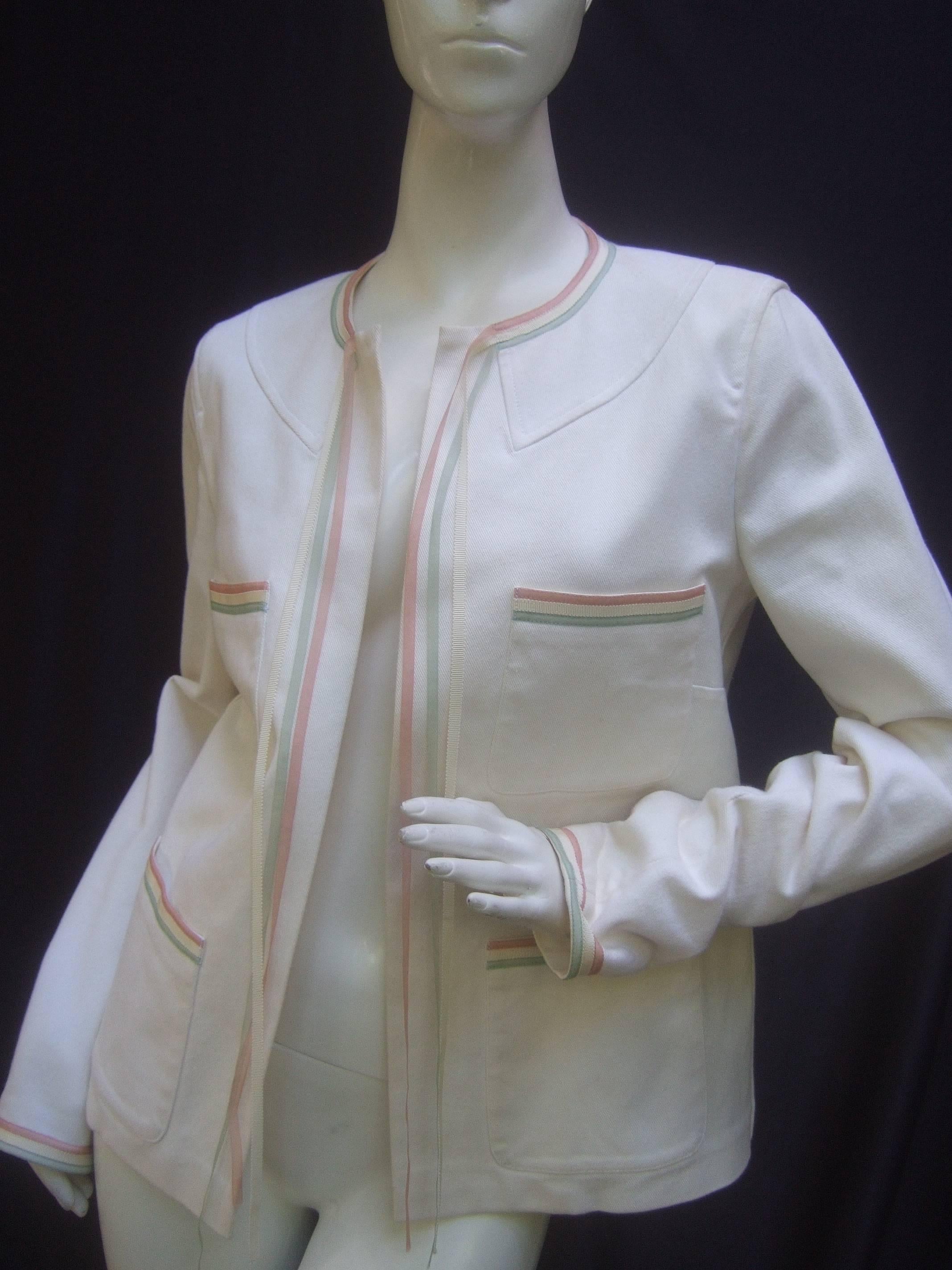 Chanel Crisp white cotton ribbon trim jacket Size 40
The stylish Chanel jacket is embellished with sinuous 
ribbons that cascade down from the front neckline

The four pockets and sleeve cuffs are accented with the
same trio of ribbons. The sheer