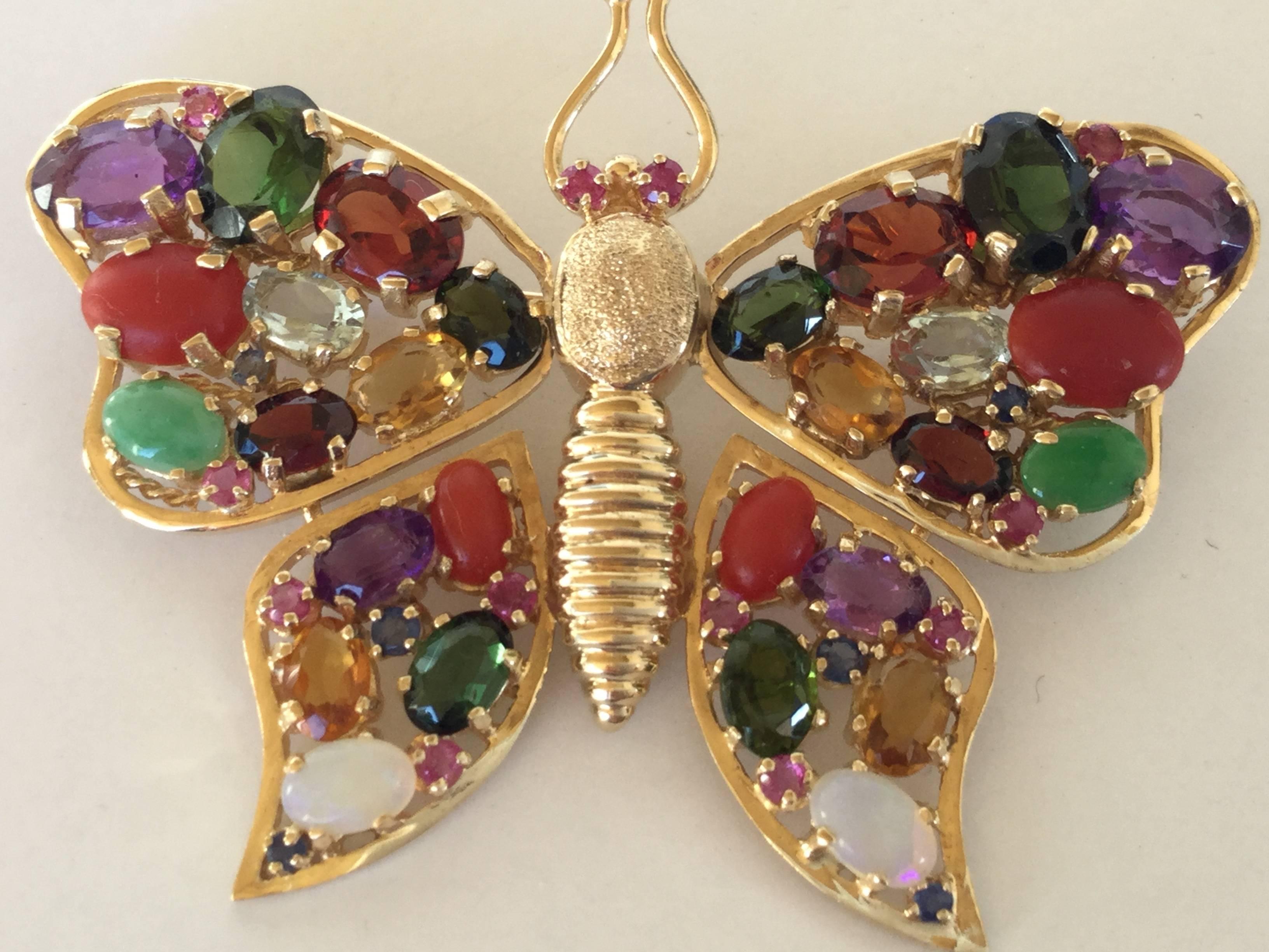 Dazzling 1960's butterfly brooch crafted of 14kt yellow gold. The entire surface if just encrusted in gemstones both faceted and cabochon.
There are 4 garnets, 6 tourmalines, 4 amethysts, 2 aquamarines, 4 carnelians, 2 opals, 4 citrines, 10 small