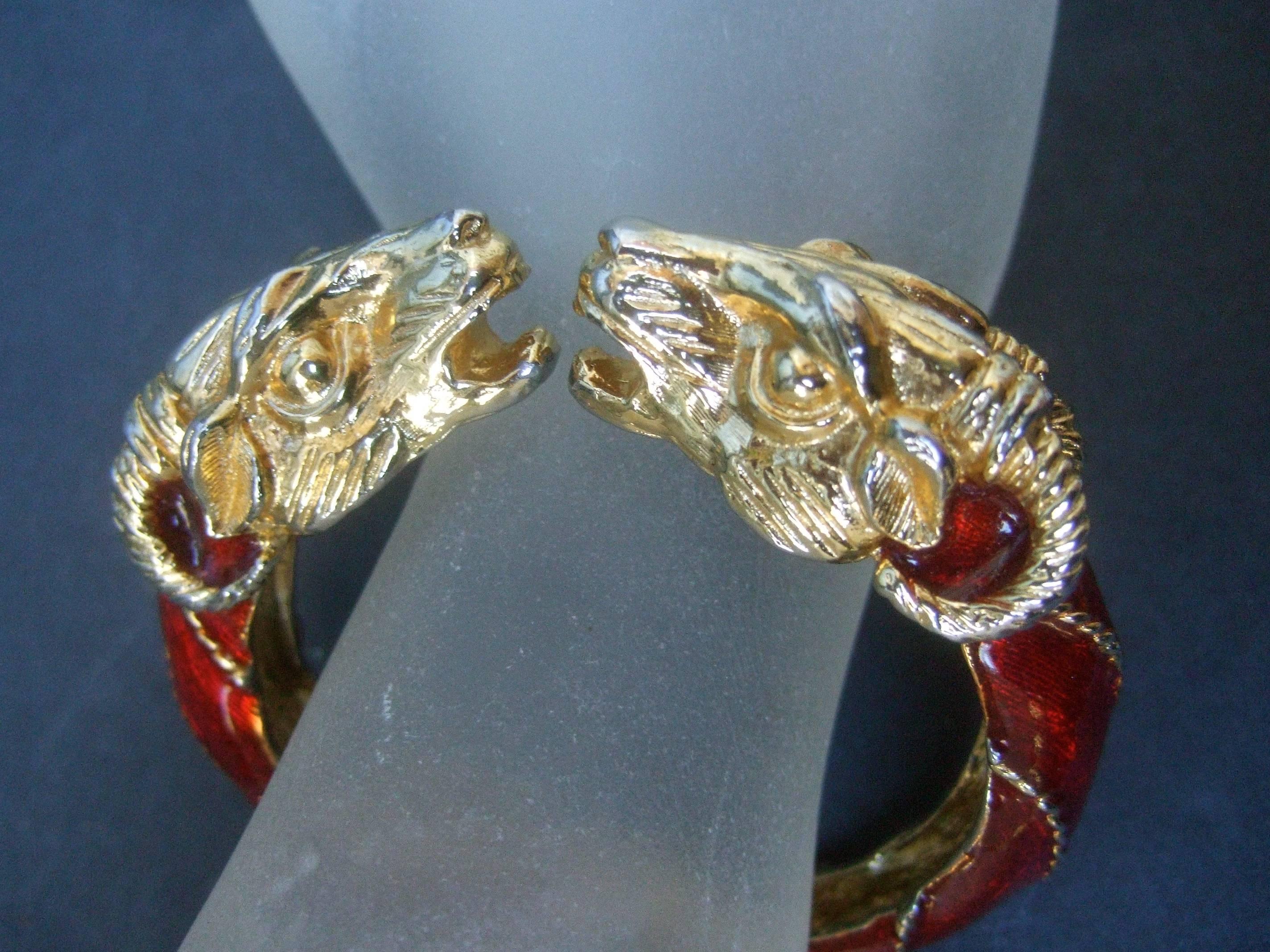 Gilt metal crimson enamel rams head bracelet by Donald Stannard 
The unique coiled hinged bracelet is designed with a pair
of stylized gilt metal rams heads

The sides of the bracelet are sheathed in red enamel lacquer 
juxtaposed with striated