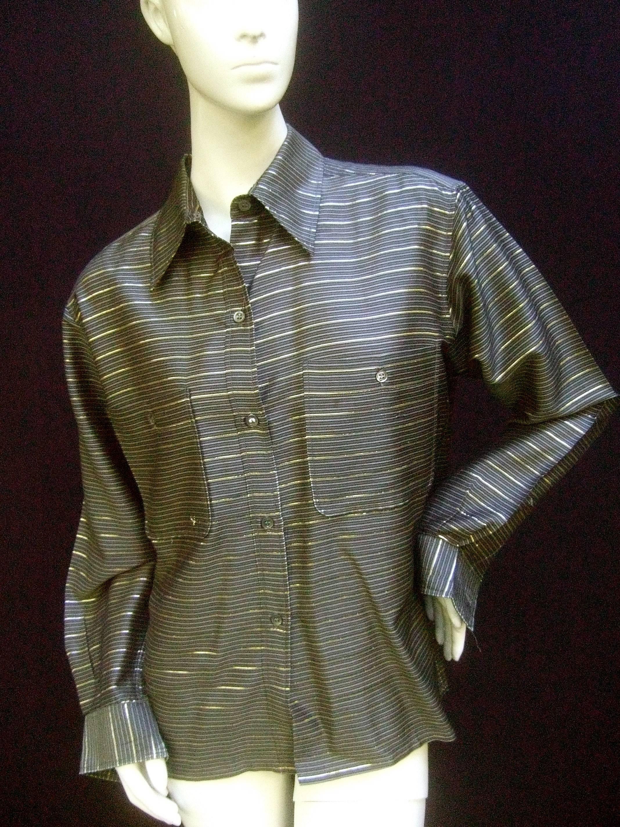 Saint Laurent Rive Gauche gold metallic striped gray blouse c 1970s
The stylish blouse is designed with a series of horizontal 
stripes in muted silvery gray colors

Juxtaposed with luminous gold metallic stripes throughout 
The shirt style blouse