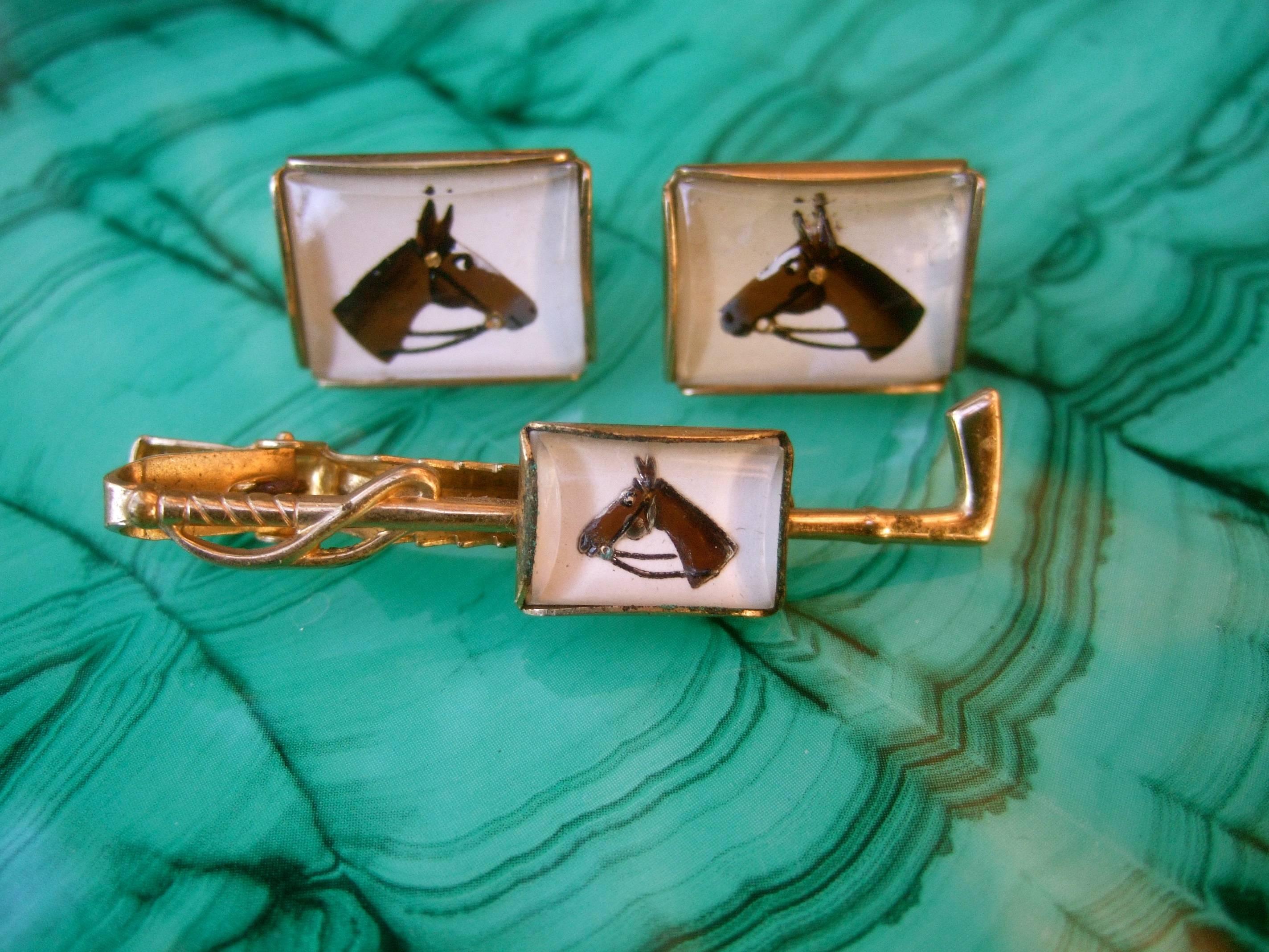 1950s Glass equine tie bar and cufflinks set 
The stylish vintage cufflinks and tie bar are designed
with the silhouette of a horse figure encased under glass

The tie clip is designed in the shape of a riding crop
Designed with gilt plated metal 