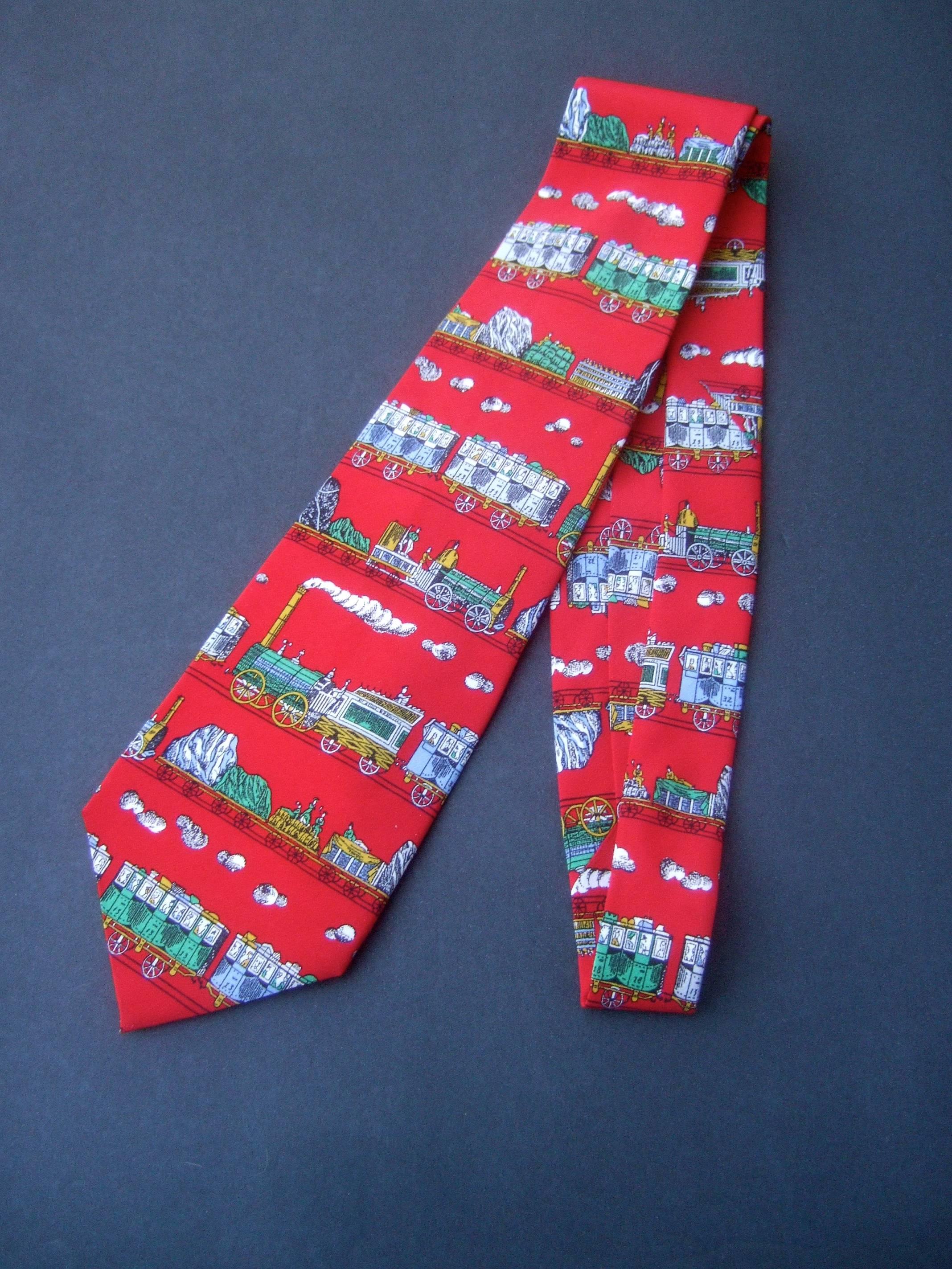 Fornasetti Italian silk locomotive train necktie c 1990s
The whimsical Italian necktie is illustrated with a series
of vintage style train cars 

The collection of train cars are set against a vibrant
red silk background

Makes a stylish bold