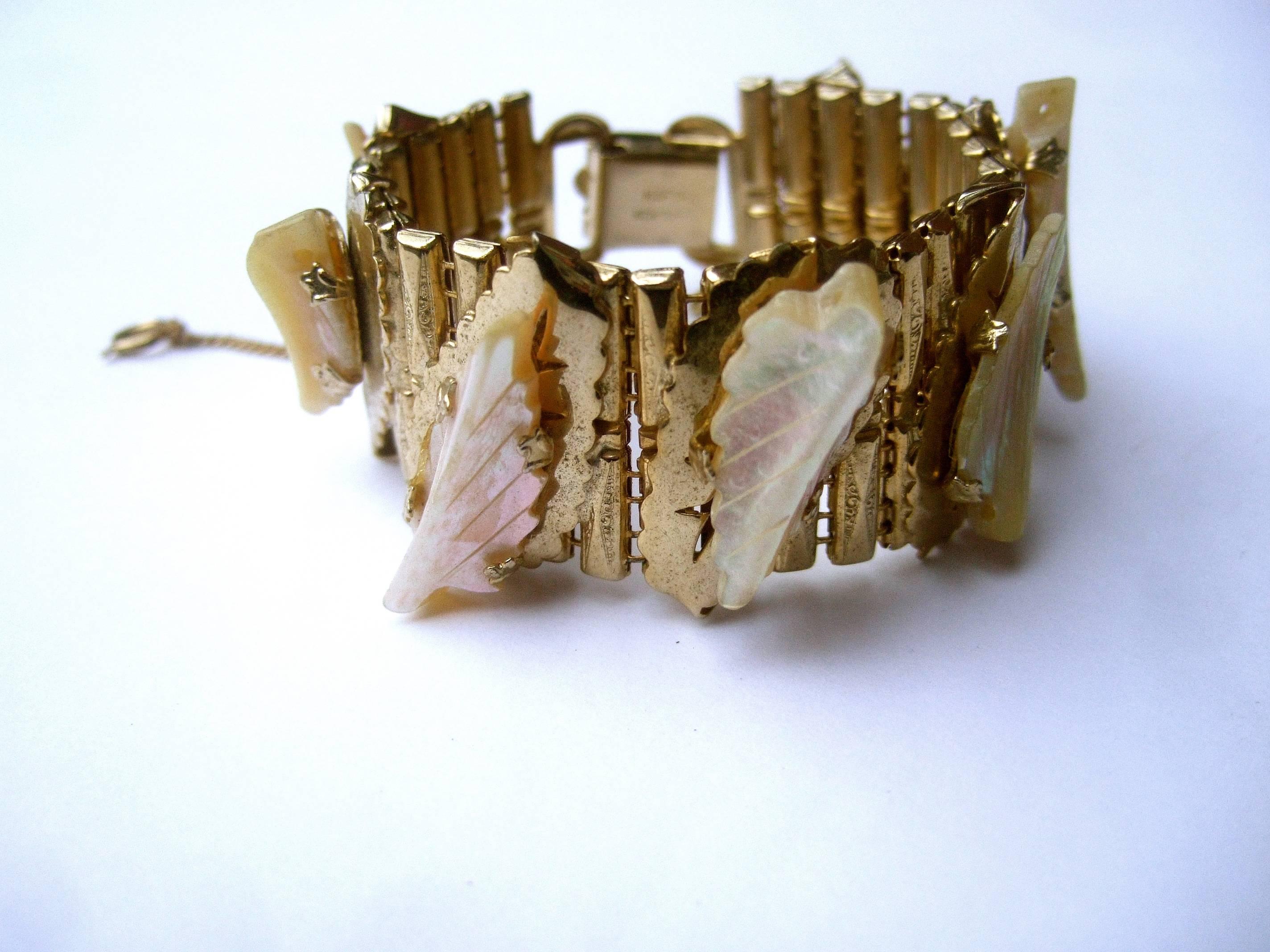 Carved mother of pearl gilt metal link bracelet designed by Kafin New York c 1960s
The elegant midcentury bracelet is designed with a series of carved 
mother of pearl leaves with etched lines

Each of the carved mother of pearl leaves is adhered to