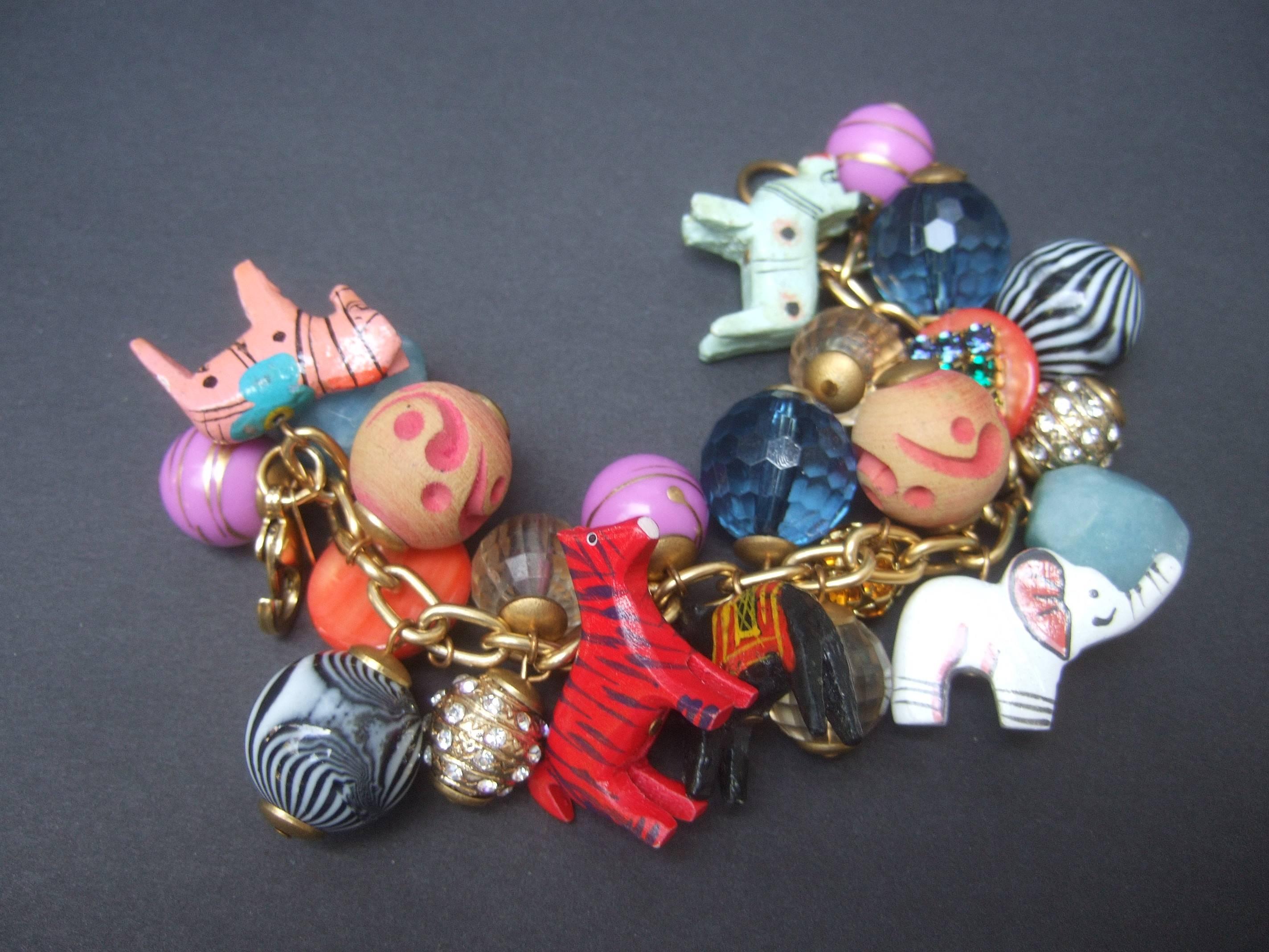Chunky jungle animal dangling bauble charm bracelet by Lenora Dame
The unique charm bracelet is embellished with a collection  
of carved wood jungle animals with enamel detail

Elephants, zebras, horses, and canine creature charms are interspersed