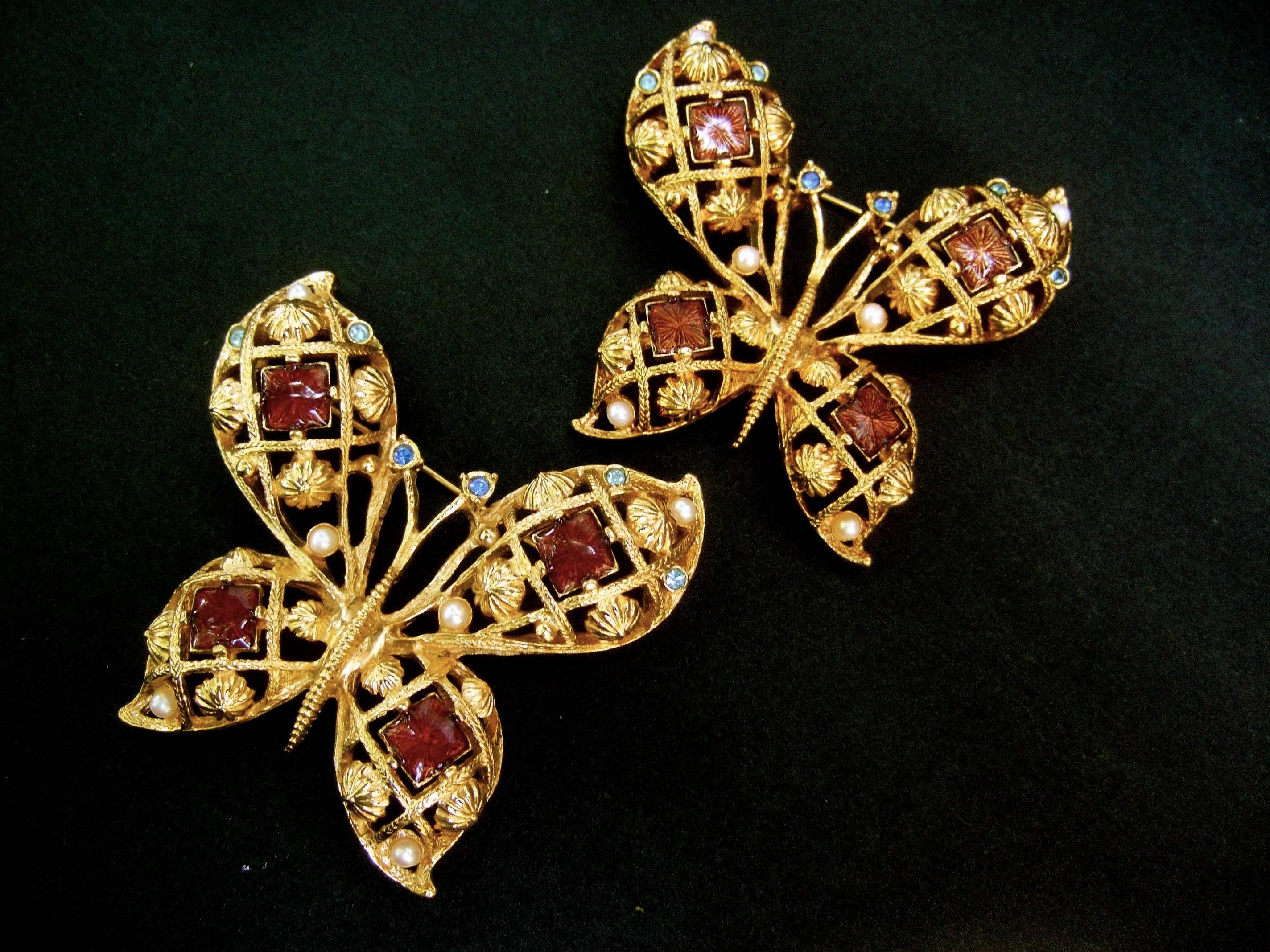 Pair of jeweled enamel gilt metal butterfly brooches c 1980s
The elegant gold metal butterflies are embellished 
with tiles of shiny enamel in muted burgundy 
and light mocha brown 

One of the brooches is designed with muted burgundy 
and the other