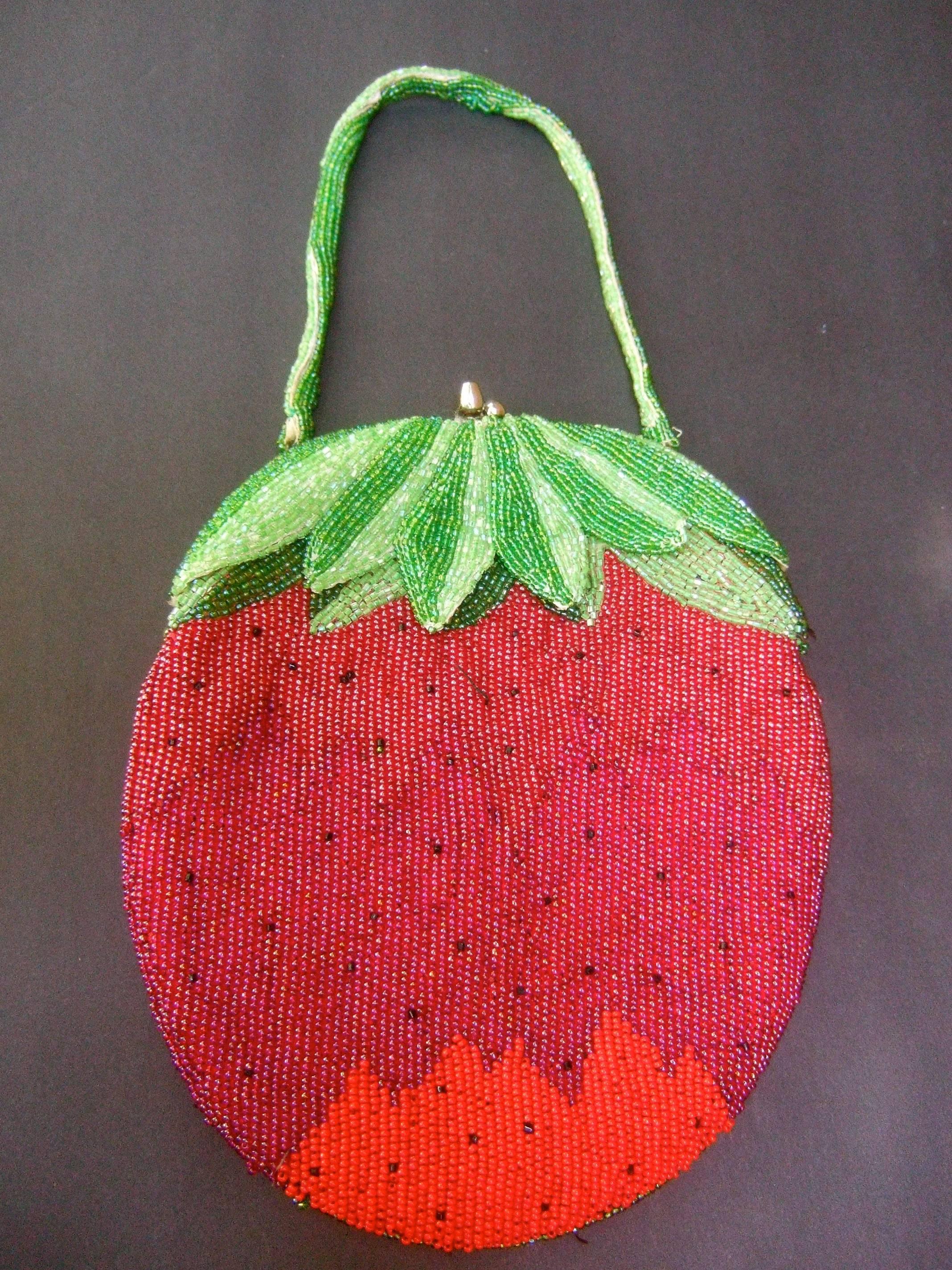 Whimsical glass beaded strawberry evening bag c 1970s
The unique glass beaded purse is designed with rows
of intricate glass beading throughout

Suspended from a matching green glass beaded handle 
The interior is lined in red satin designed with a