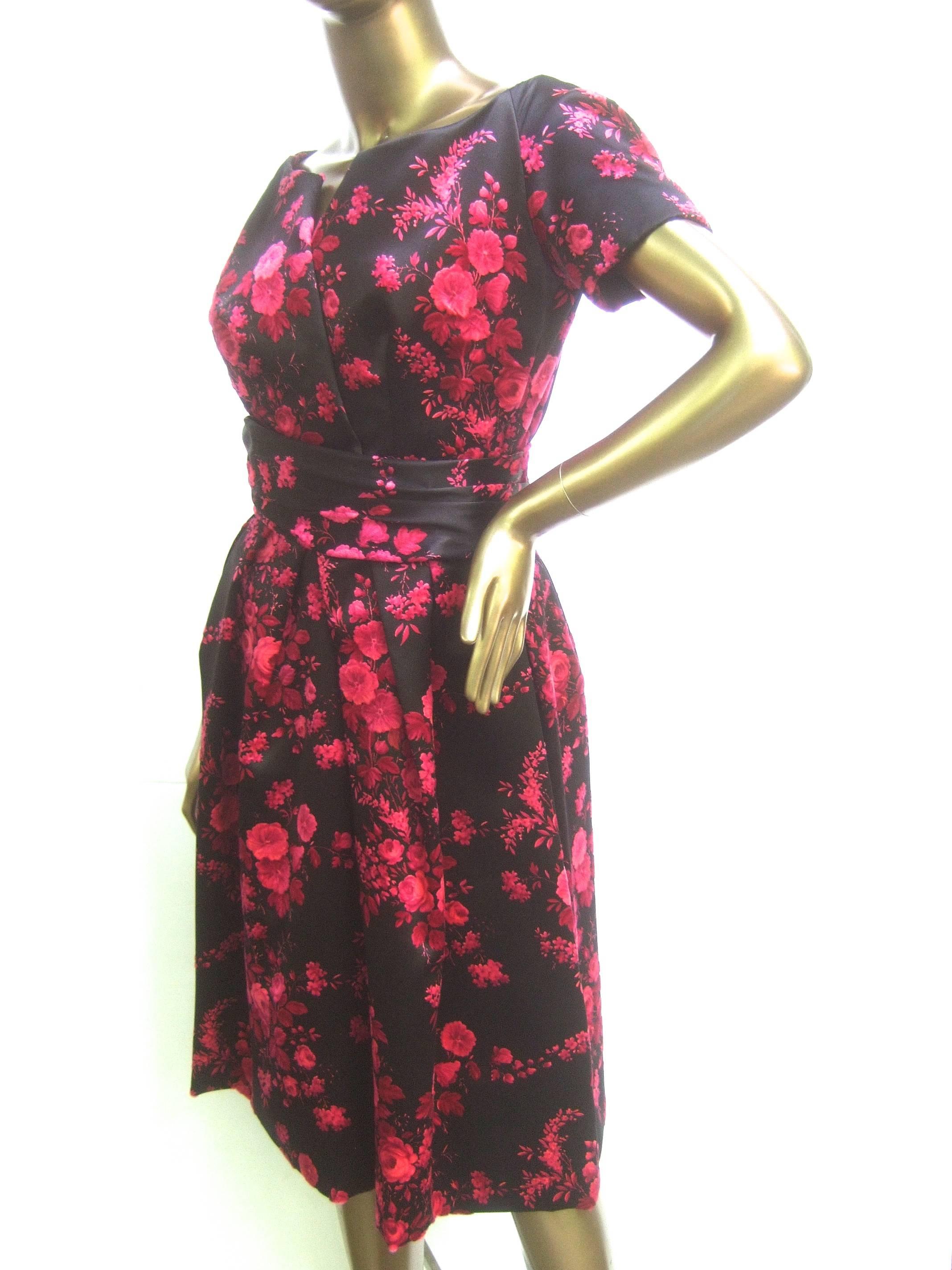 Christian Dior Couture satin floral print cocktail dress c 1960
The elegant couture dress is designed with black 
satin fabric infused with vibrant fuchsia flower blooms

Designed with a matching fabric belt that hooks 
The chic couture dress is