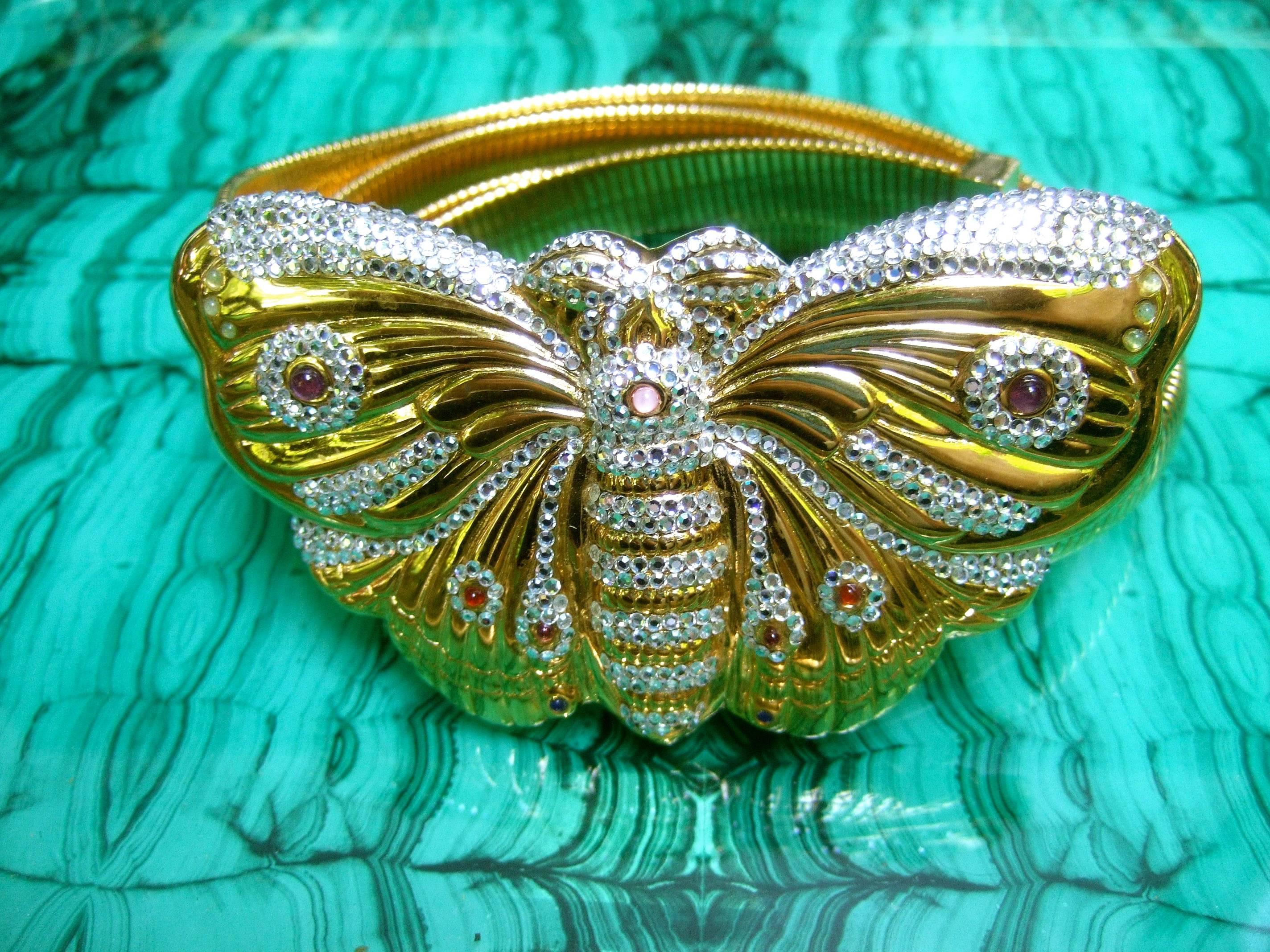 Judith Leiber Exquisite massive jeweled butterfly belt c 1980s
The opulent belt is adorned with a large scale gilt metal 
butterfly buckle encrusted with glittering diamante crystals;
combined with clusters of tiny glass cabochons in a myriad
of