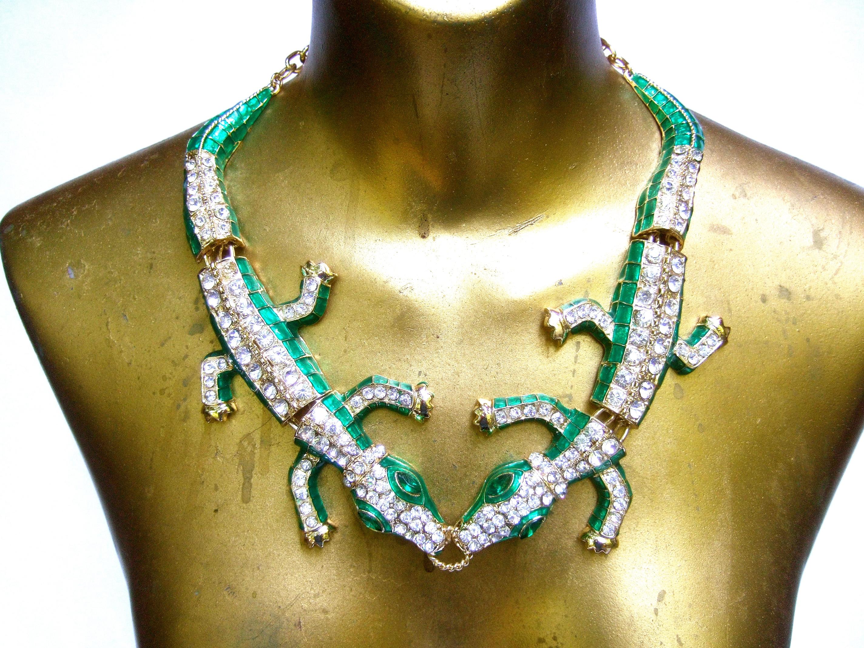 Crystal enamel articulated gilt metal alligator necklace c 21st C
The unique pair of hinged alligators are encrusted with
rows of glittering diamante crystals 

The articulated bodies are sheathed with emerald green enamel 
The alligator's eyes are