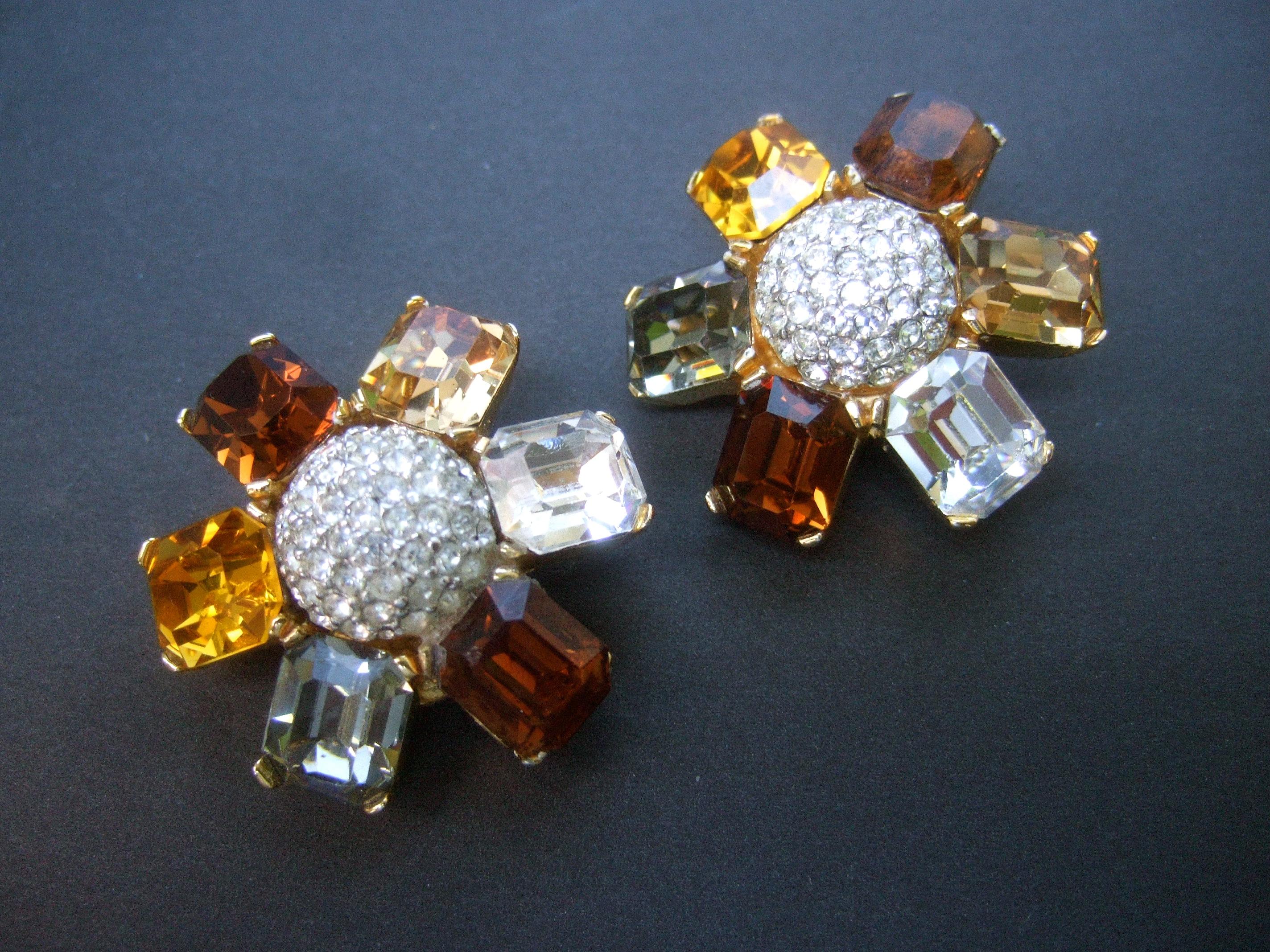 Ciner Autumn crystal large scale clip on floral earrings c 1980
The elegant designer earrings are embellished 
with six rectangular prong set crystals in a myriad 
of colors; ranging from golden amber, smokey brown,
gray and clear  

The center of