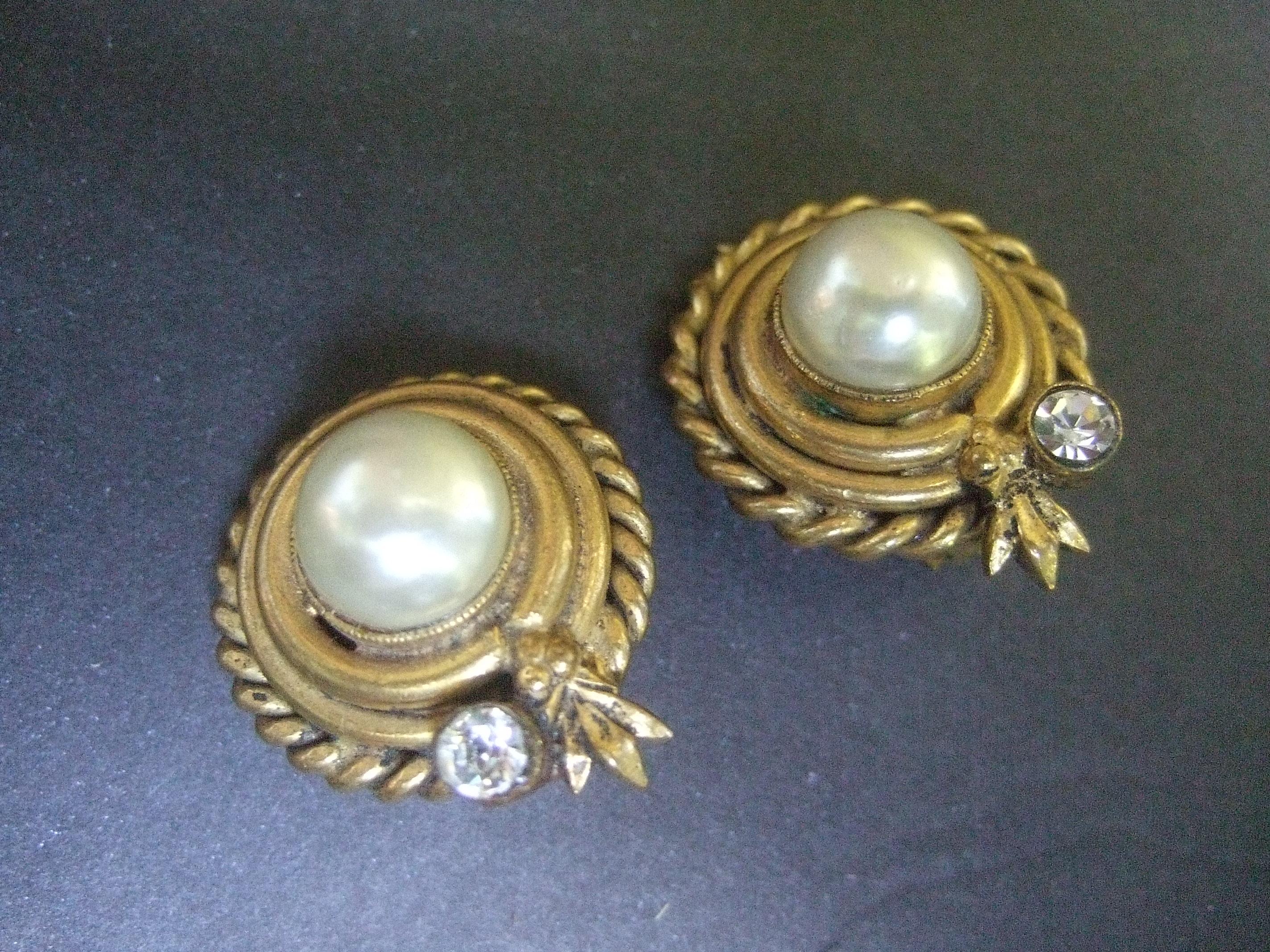 Chanel Elegant glass enamel pearl gilt metal clip-on earrings c 1980s 
The chic button style earrings are adorned with a luminous 
glass enamel in the center

The outer edges are designed with brass-tone gilt metal; framed with a braided rope