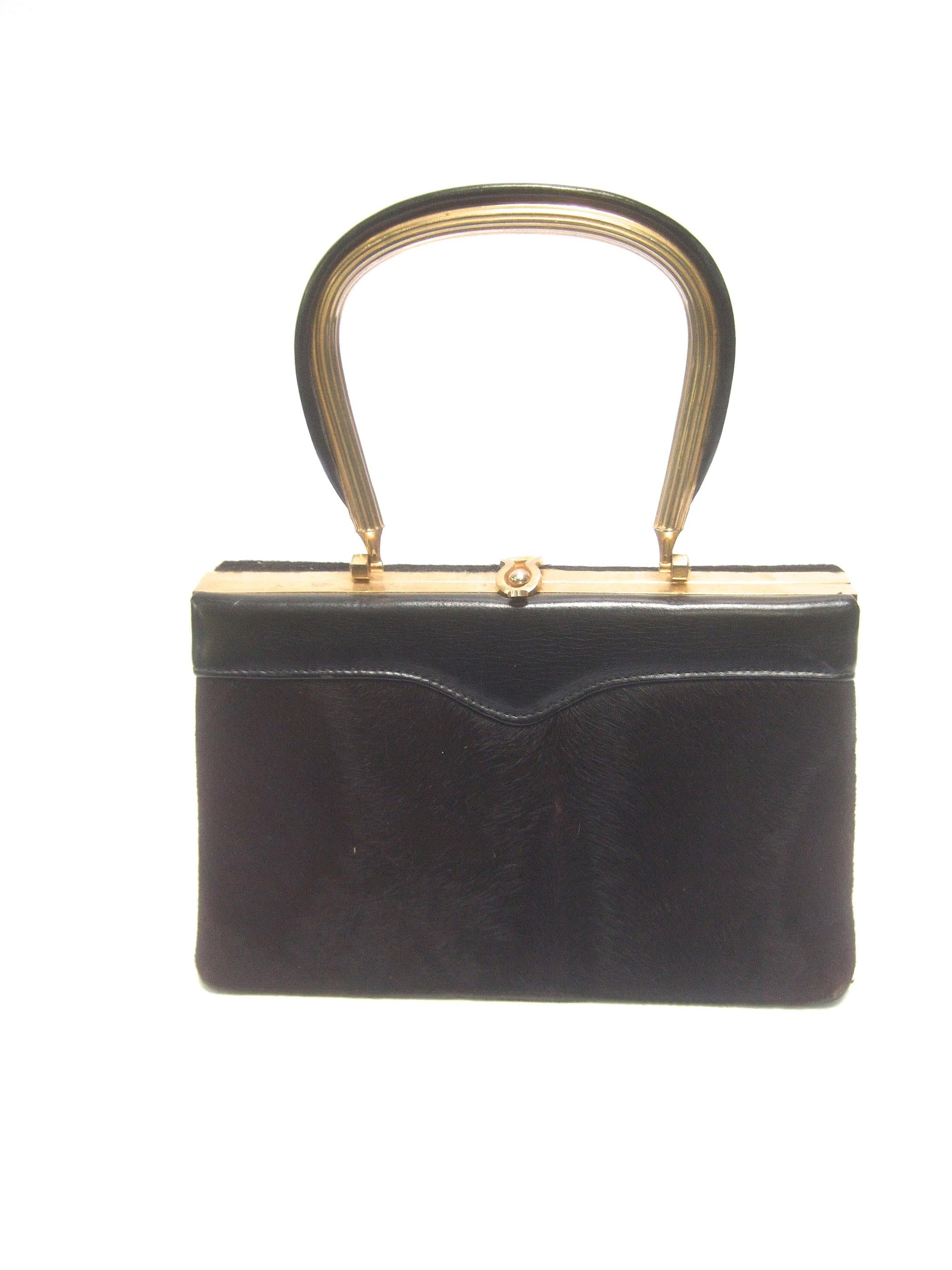 Diminutive chocolate brown pony fur handbag c 1970
The charming small size handbag is covered 
with dark brown pony fur on the front exterior

Running across the front upper section of the 
handbag is a black leather panel. The gilt metal
swivel