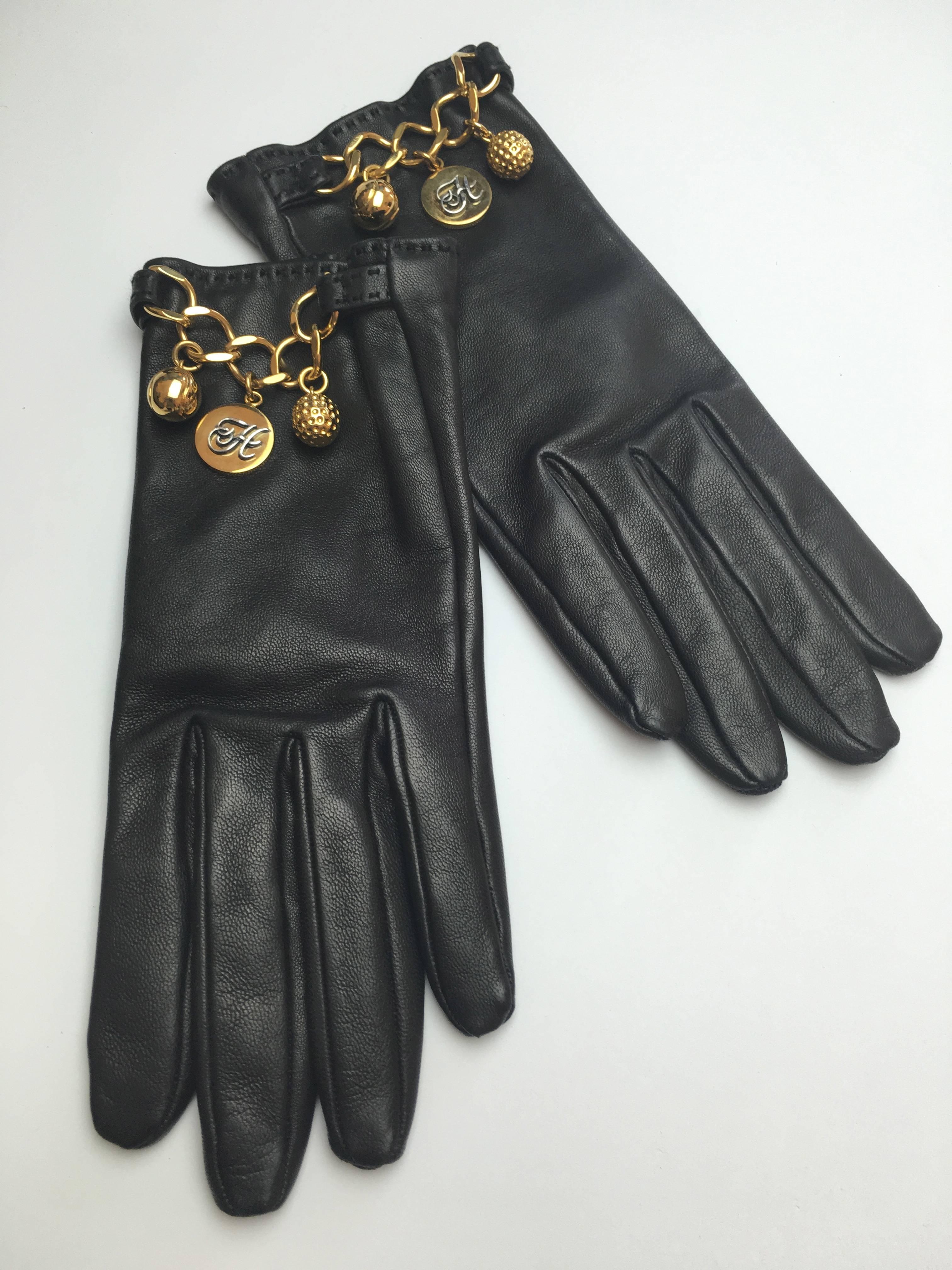 Impossible to find Hermes black lambskin gloves embellished with a gilded chain and three gilded charms including a Hermes logo medallion.

So sleek and elegant. Buttery soft leather in mint condition with original box.

Glove size:  6.5  So,