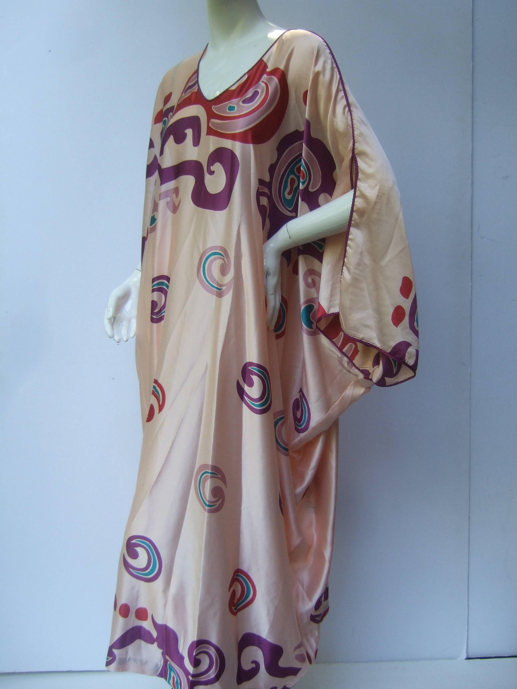 Mary McFadden Mod abstract print caftan 
The spectacular print is a collage of bold 
swirls set against a luminous silky peach
background

The graphic print is a spectrum of dark
purples, deep reds with hints of teal
blue / green colors 