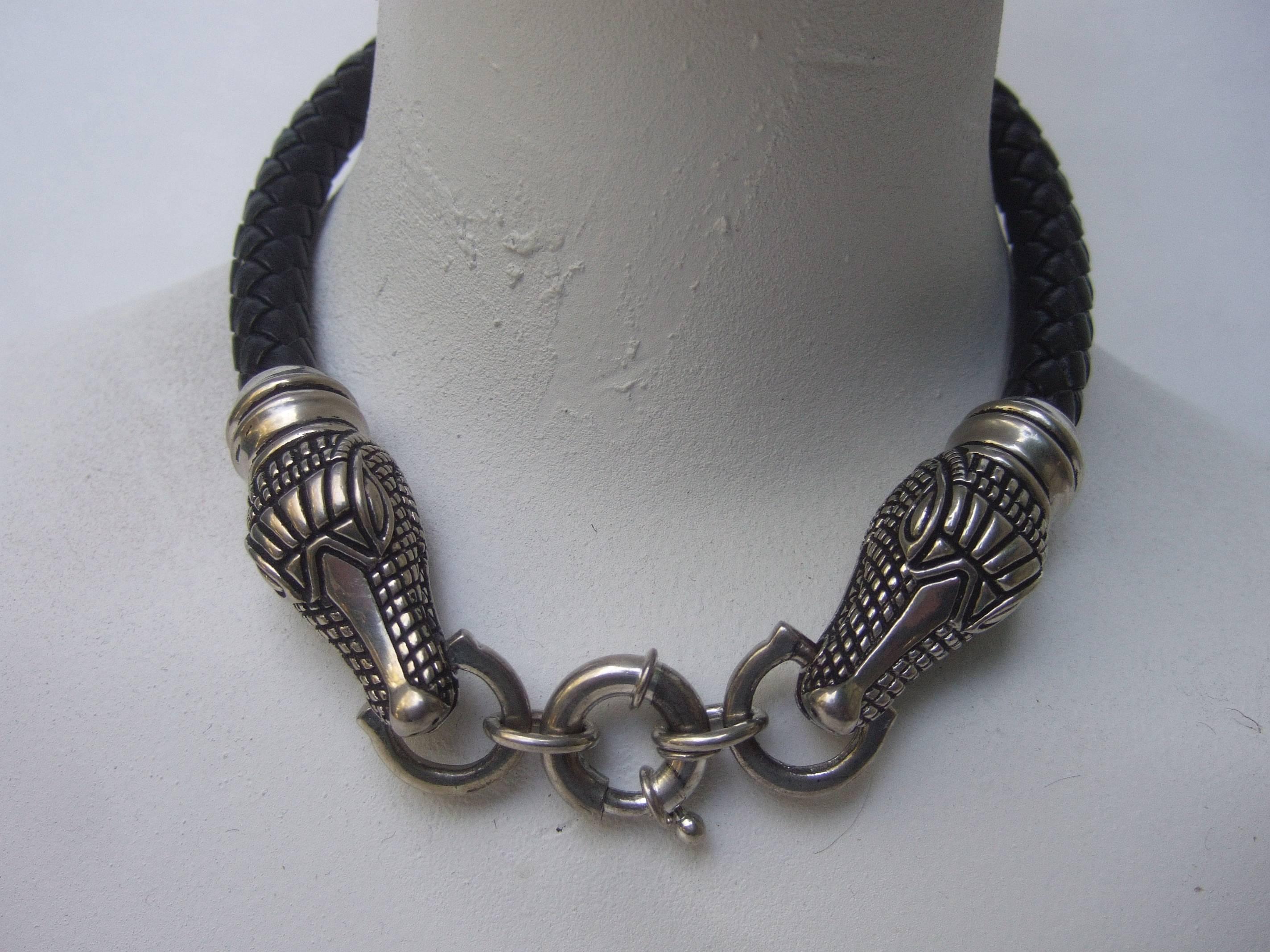 Sleek braided leather alligator head choker necklace
The unique choker necklace is designed with a pair
of silver metal alligators heads adhered to a black
leather braided cord. The metal alligator heads have
etched and impressed designs that