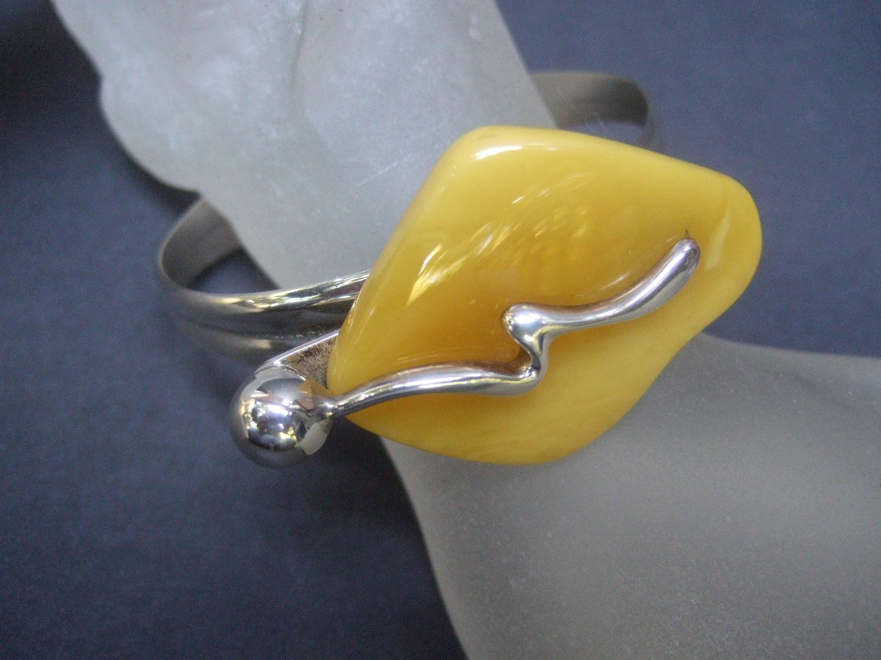 Sterling silver baltic amber modernist style bracelet
The artisan bracelet is designed with a large slice
of baltic amber adhered to a sterling metal band

The slice of baltic amber is designed with sterling
scrolled streak across the top with