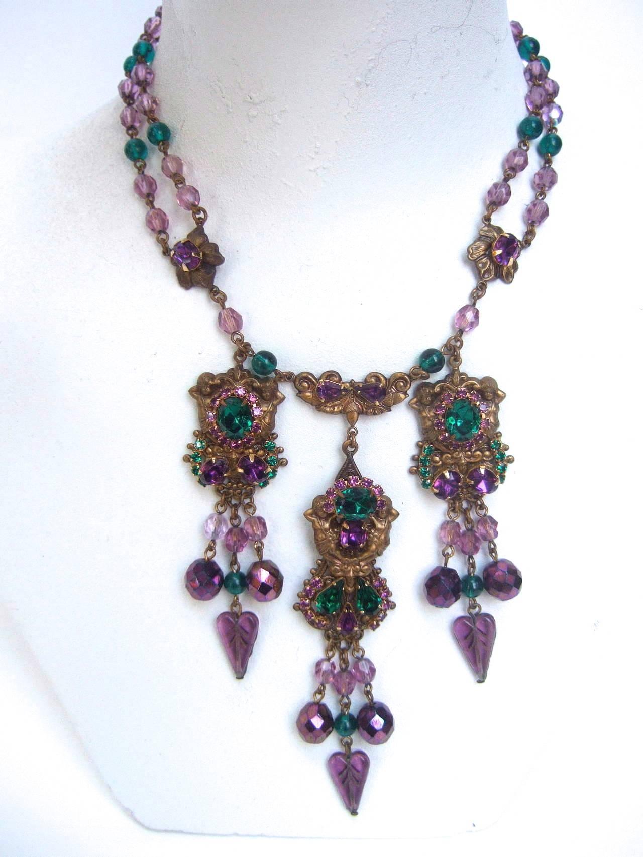 
Exquisite crystal jeweled tiered necklace  c1950's.

This romantic necklace is encrusted with a glittering collage of
emerald green and amethyst faceted crystals.

The center of this extraordinary necklace is designed with three dangling