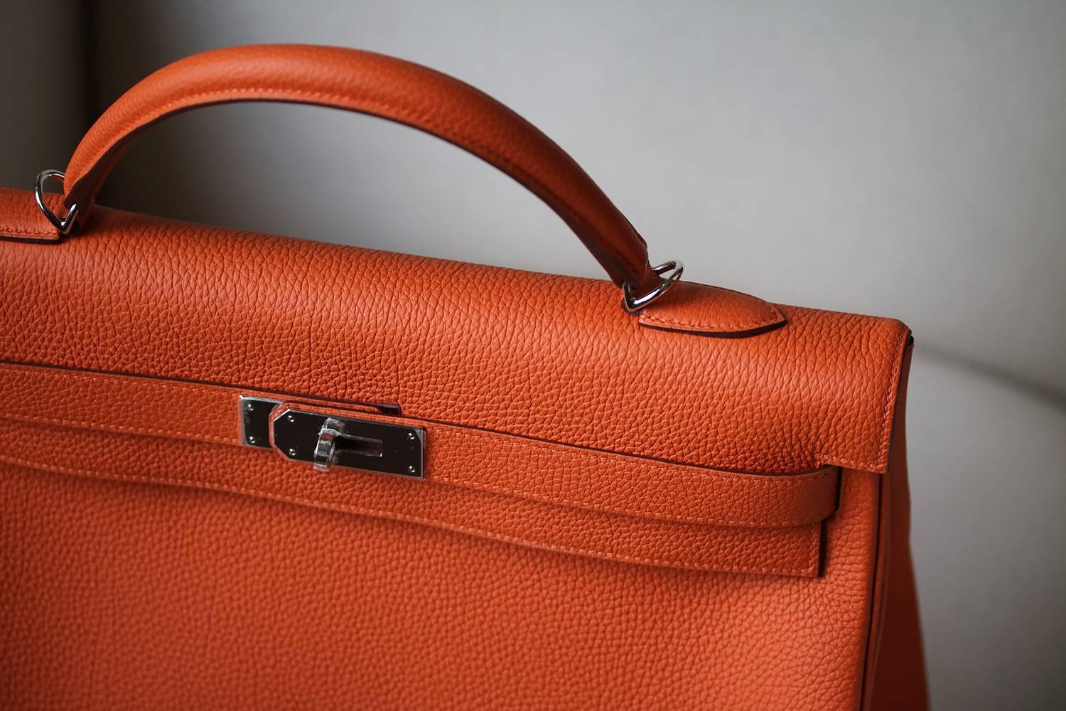 Hermès 40cm Kelly in orange with palladium hardware. Luxuriously rich Hermès orange colour with tonal top stitching.

Year: Date stamp is a R in a square - 2014 production.

Condition: This bag is brand-new, unworn and in its original box. Some