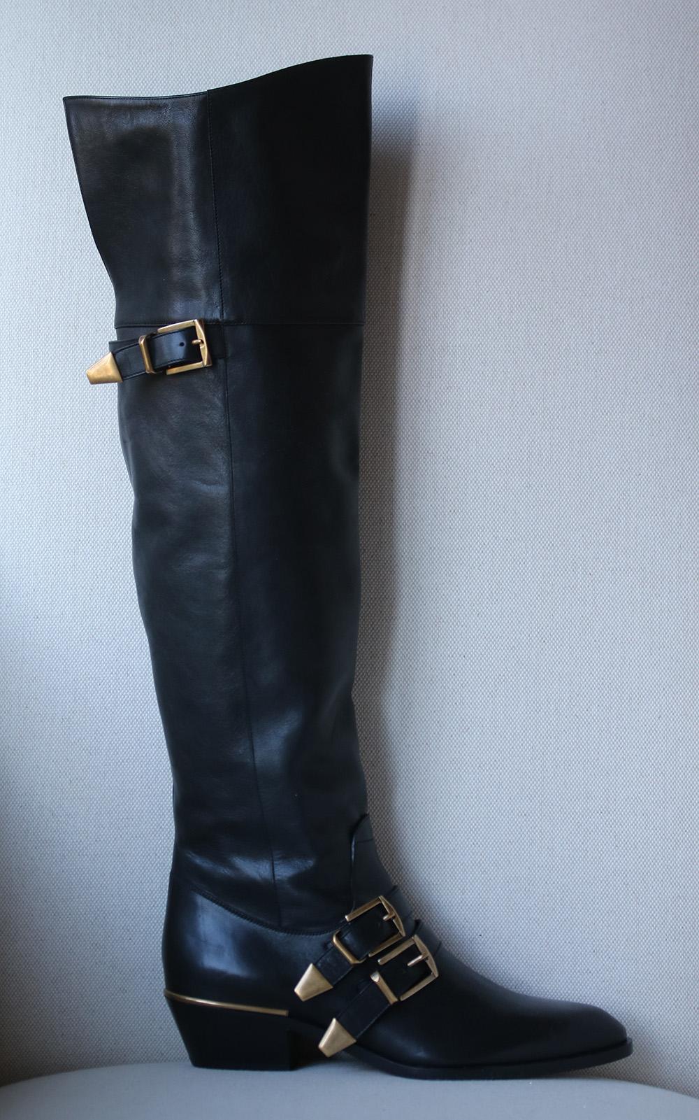 Chloé's collection conveyed a 1970s mood with minor equestrian references, as embodied by these black leather thigh-high boots. The pointed-toe, square-heeled shoes are both simple and stylish, modestly decorated with a gold-tone buckled straps.