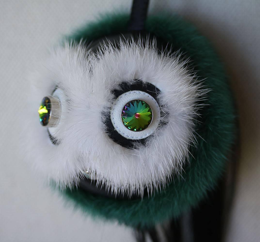 Charm Bag Bugs in black leather and mink fur in white and green. Two luminous green crystals and a metal conical stud create the eyes and mouth. Black calfskin lace, palladium finish spring clip and tag with engraved Fendi logo. Ideal as a charm for