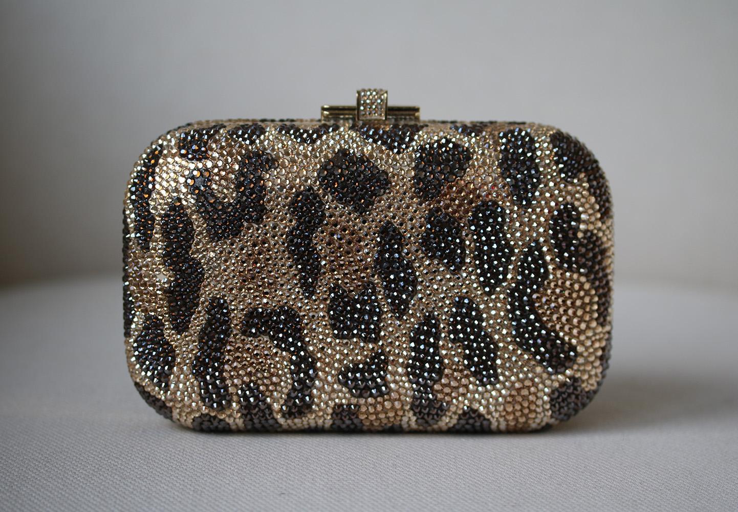 Leopard-print hard box clutch with hand-placed fine crystal embellishment. Judith Leiber clutch has a gold frame and removable chain-link handle that can be hidden inside the bag, a push-clasp at top and is fully lined in gold leather.

Dimensions: