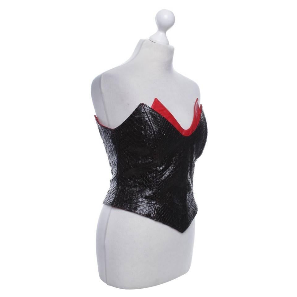 RARE and Collectible
Thierry Mugler Couture 
Black and red silk and python skin corset from Thierry Mugler Vintage featuring a strapless design, a sweetheart neckline, a fitted silhouette, a boned waist, a red silk trim and an all-over python skin