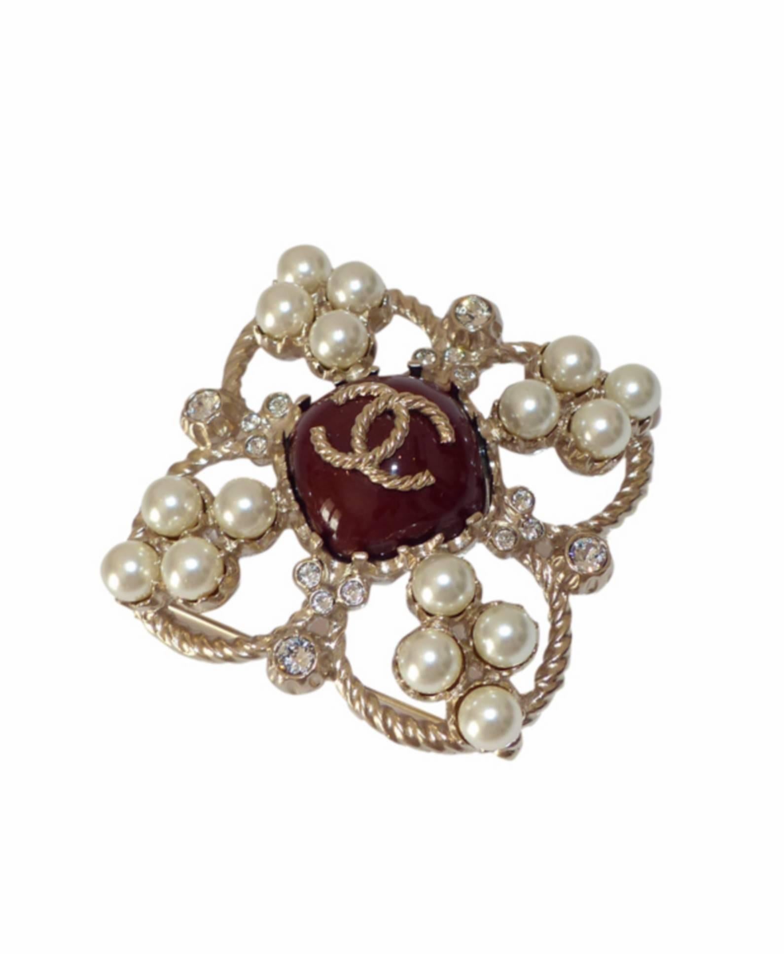 Very beautiful Chanel brooch in brushed twisted metal set with pearls and rhinestones.
Collection Paris Edinburgh
Burgundy central stone and golden metallic CC logo.
Signature on the back
Excellente Condition 
Delivered with its Chanel
