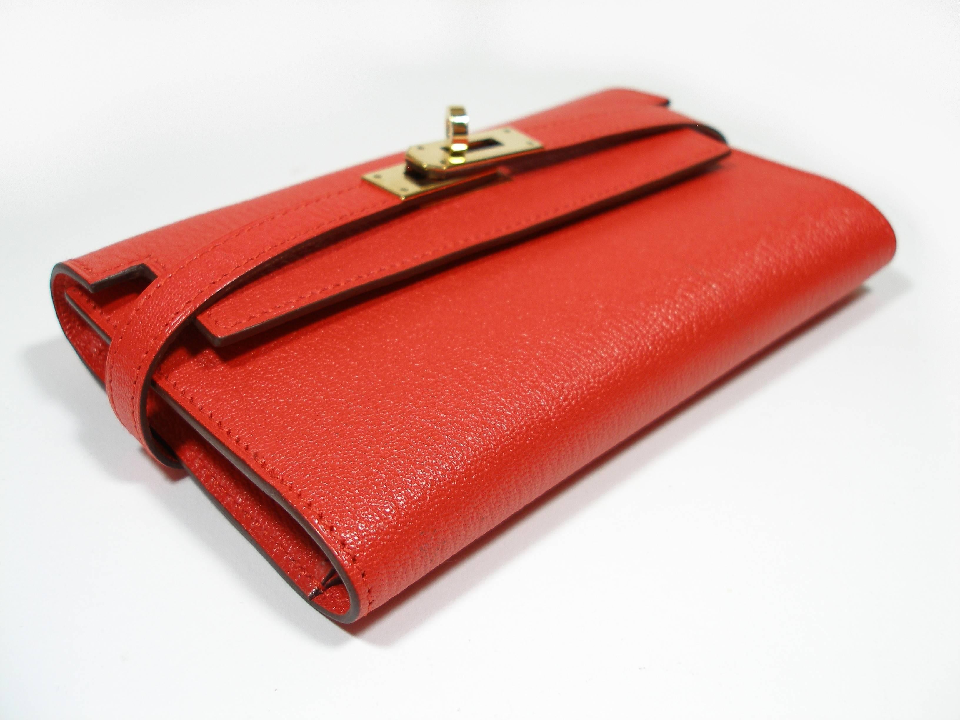 HERMES Chevre Mysore Kelly Compact Wallet Rouge Tomate and permabrass hardware. This stunning clutch wallet is finely crafted of rouge tomate chèvre goatskin leather. The front flap and polished permabrass turn lock open to a matching leather