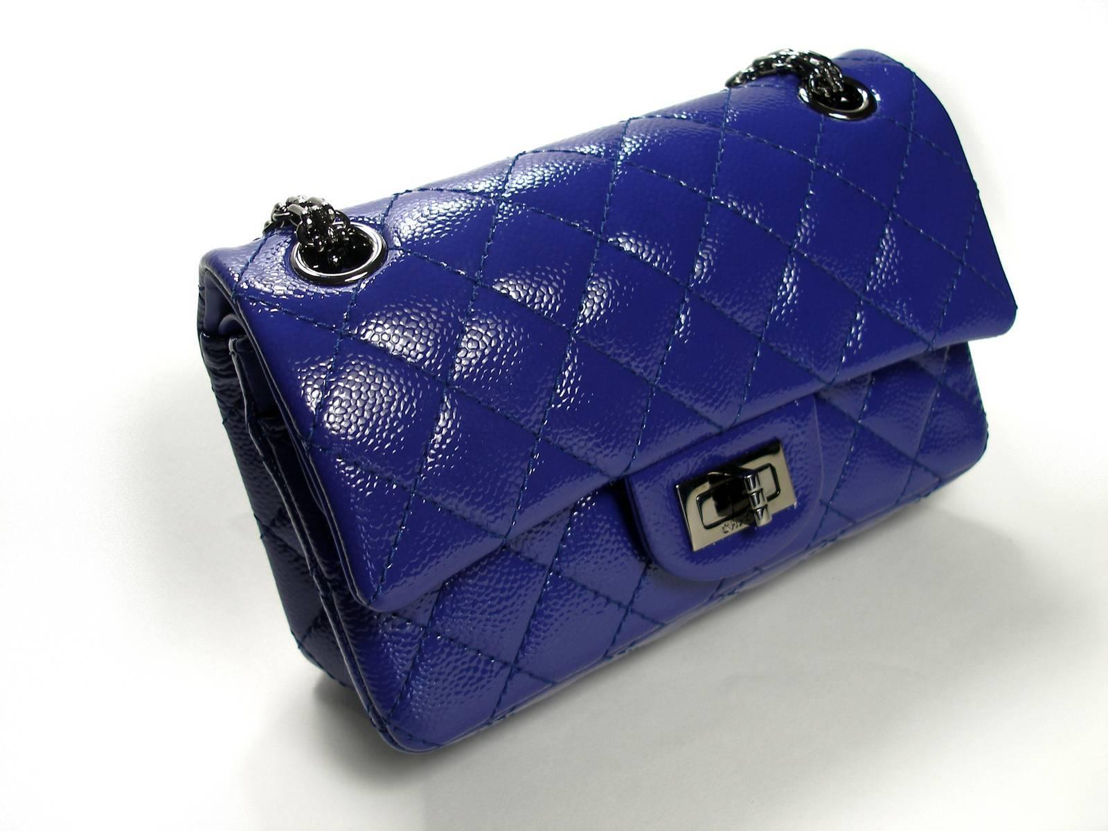 A modern and sleek bag by Chanel that is perfect for any collector or enthusiast. Glossy purple textured patent leather exterior with a quilted design. Metal grey hardware with an adjustable strap and turn lock closure. The 