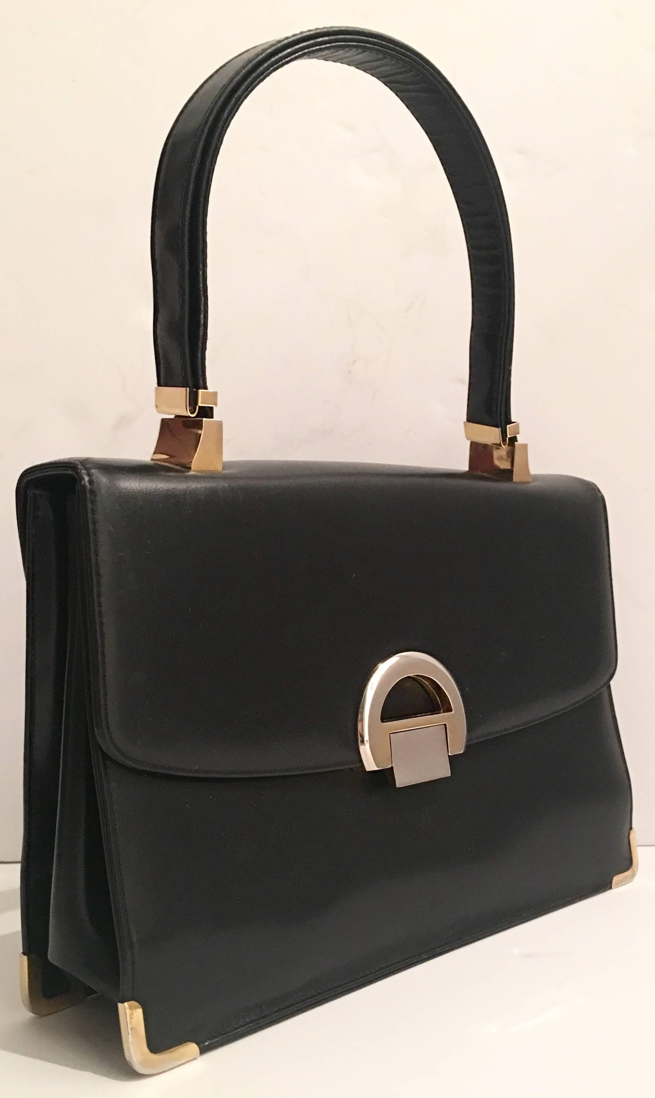 1950'S Koret black soft leather handbag with two-tone metal hardware and adjustable shoulder strap. Interior finished in vivid red with a red and gold coin purse included. There are three interior pockets, one with a zipper. Should strap drop